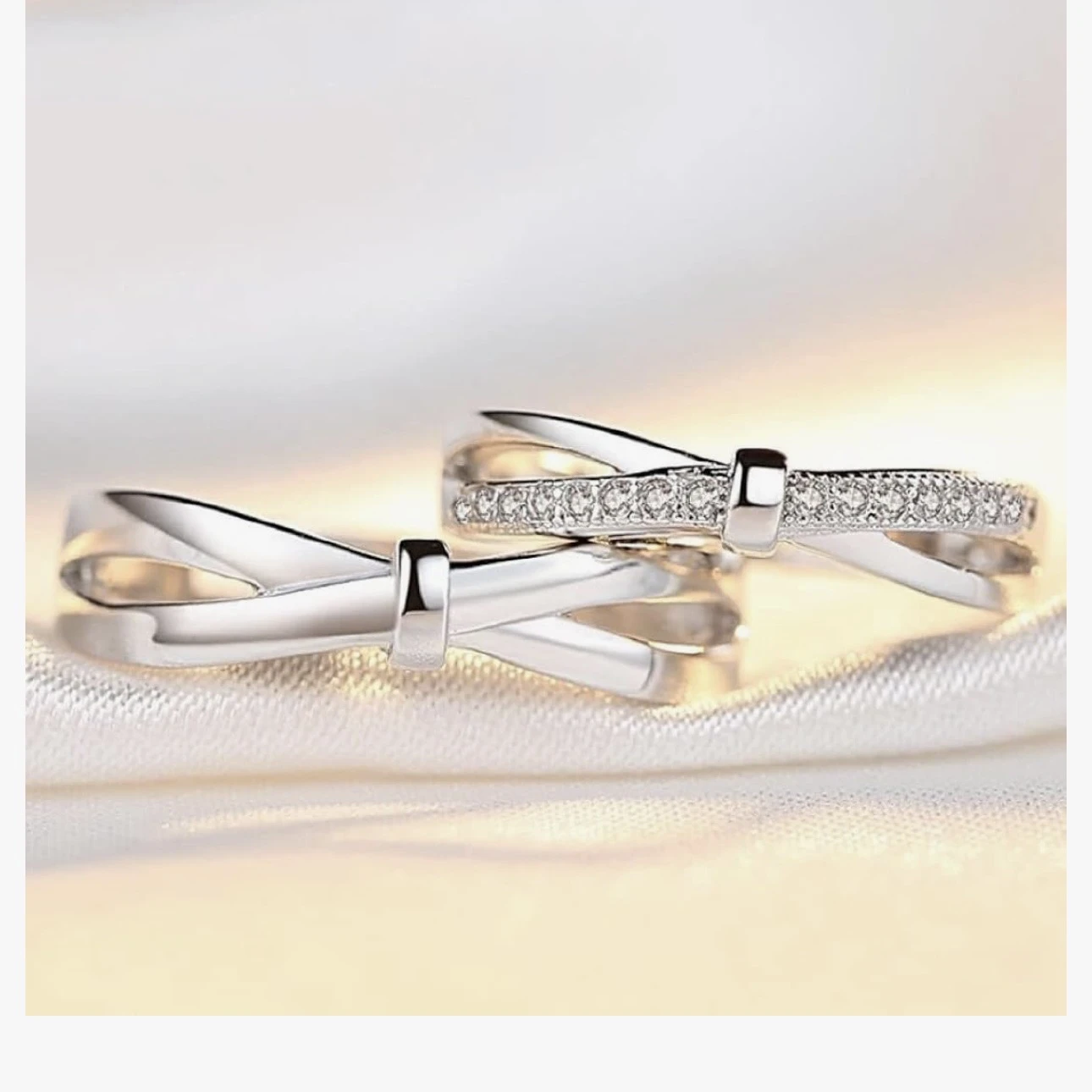 set of silver-plated, adjustable couple rings featuring a double bowknot design, with one ring studded with cubic zirconia stones.