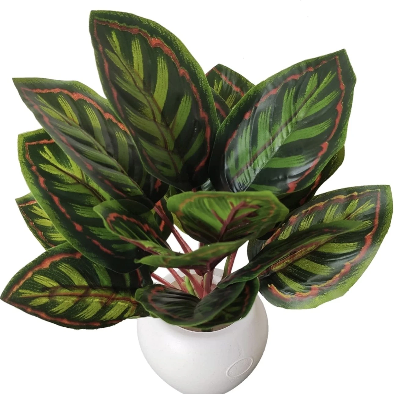 An artificial Calathea plant in a black plastic pot.