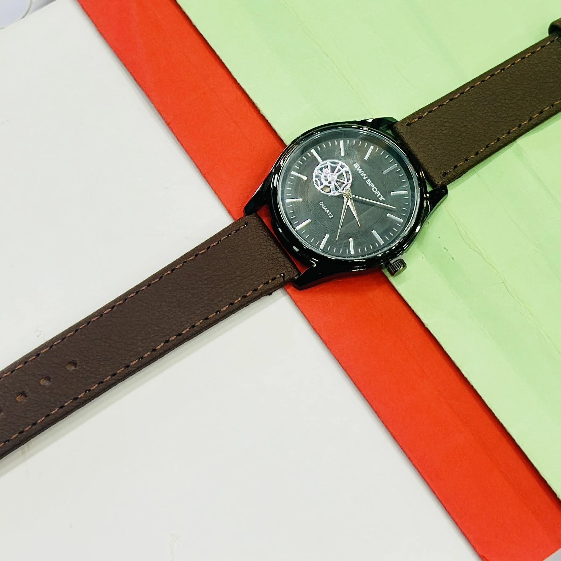 Quartz watch with a brown leather strap and a black dial.