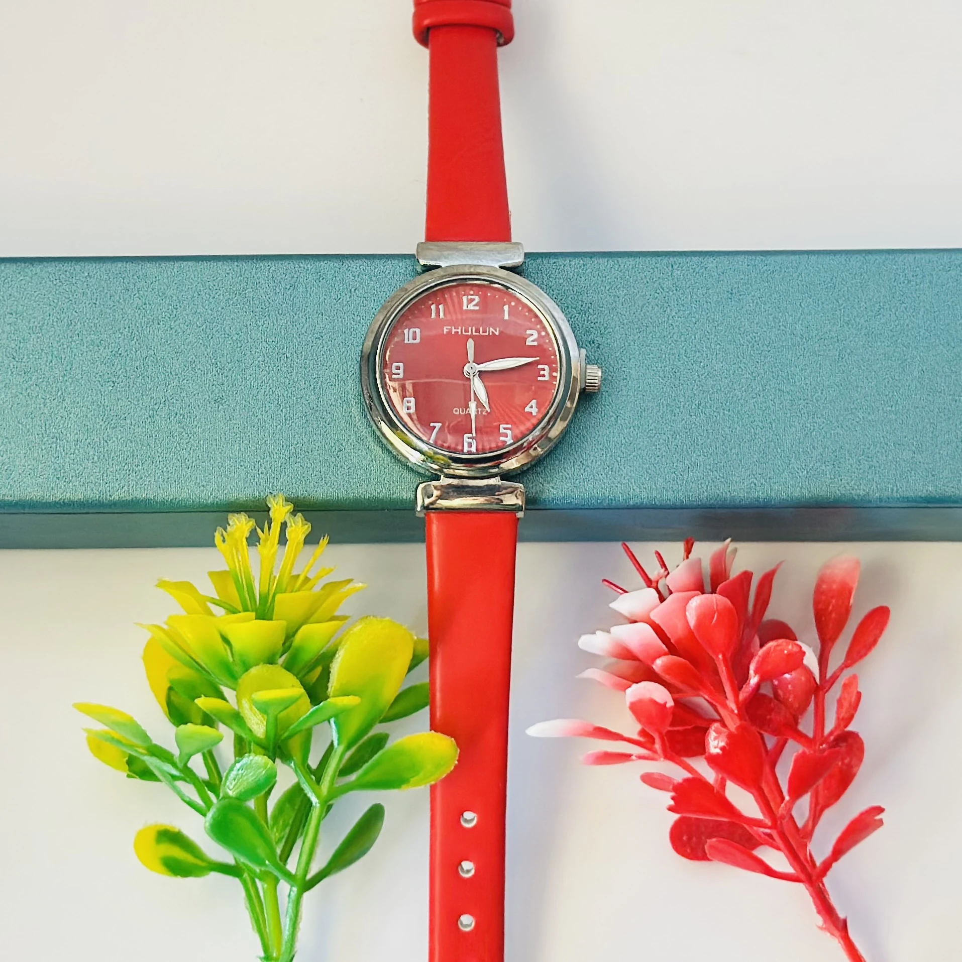 Red analog watch with a black leather strap.