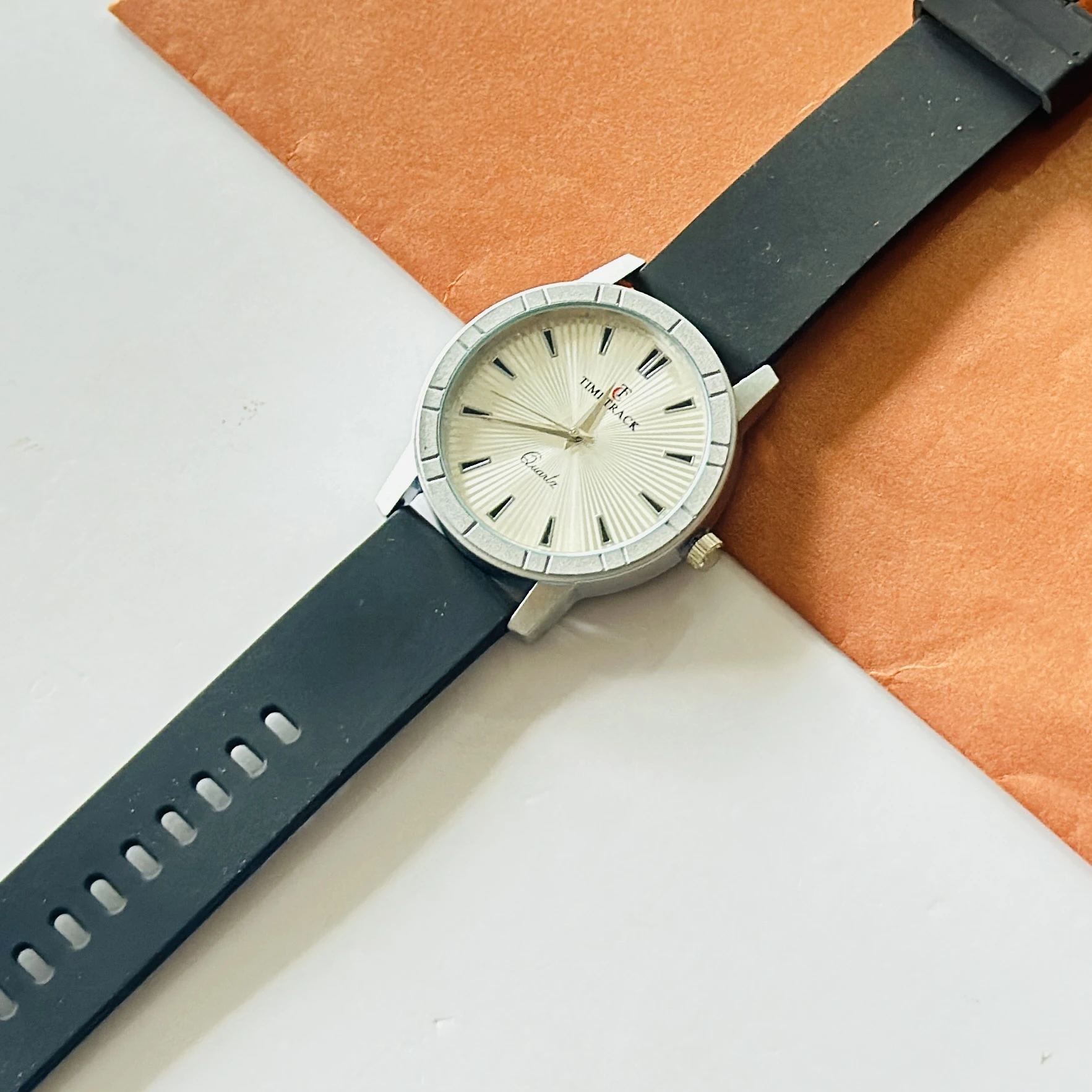 Timitrack brand quartz analog wristwatch with a silver-toned dial and a black silicone strap.