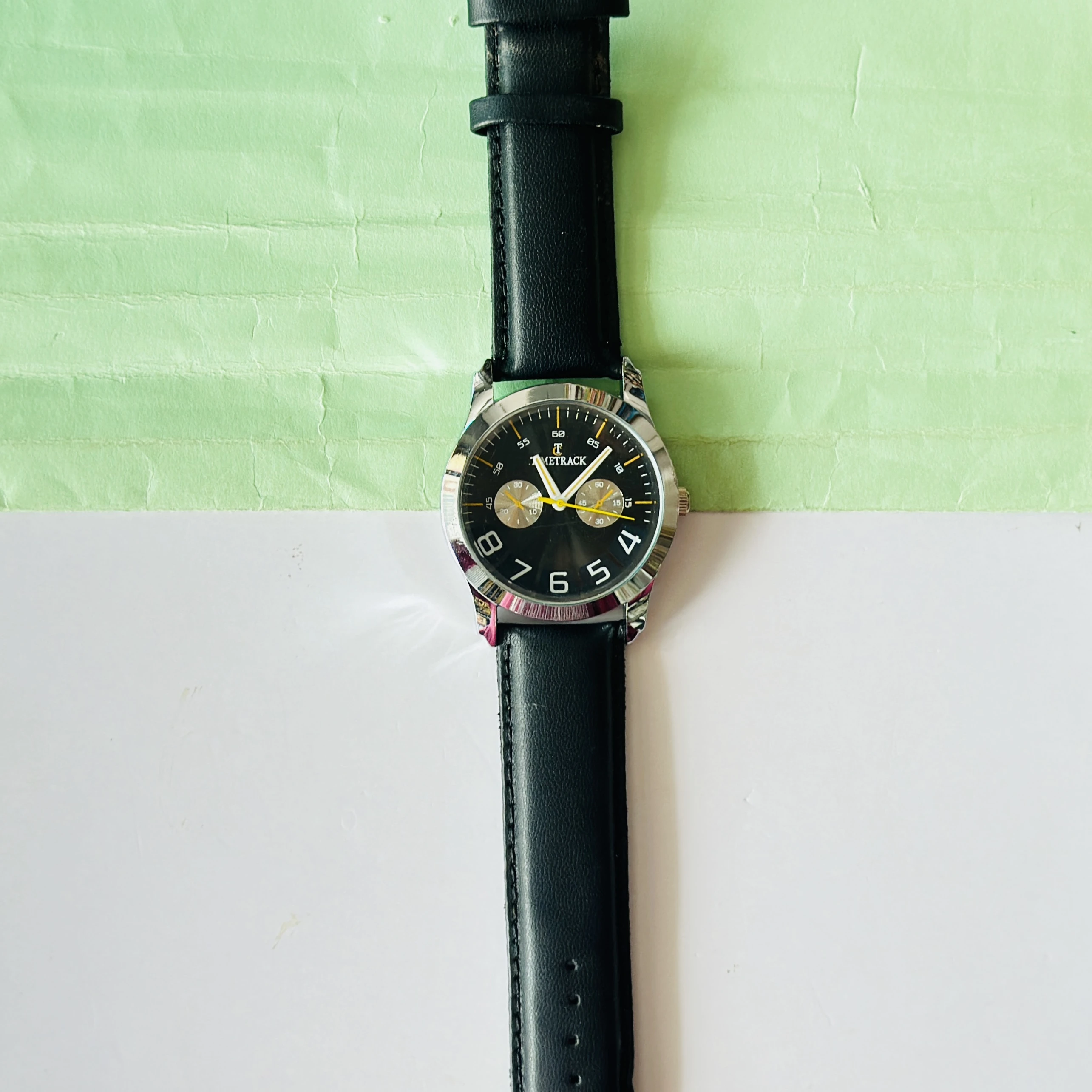 Metrack brand analog watch featuring a black dial and a black leather strap.