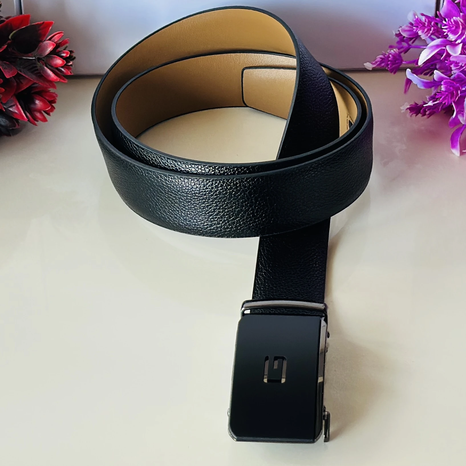 Black leather belt with an automatic/ratchet buckle.