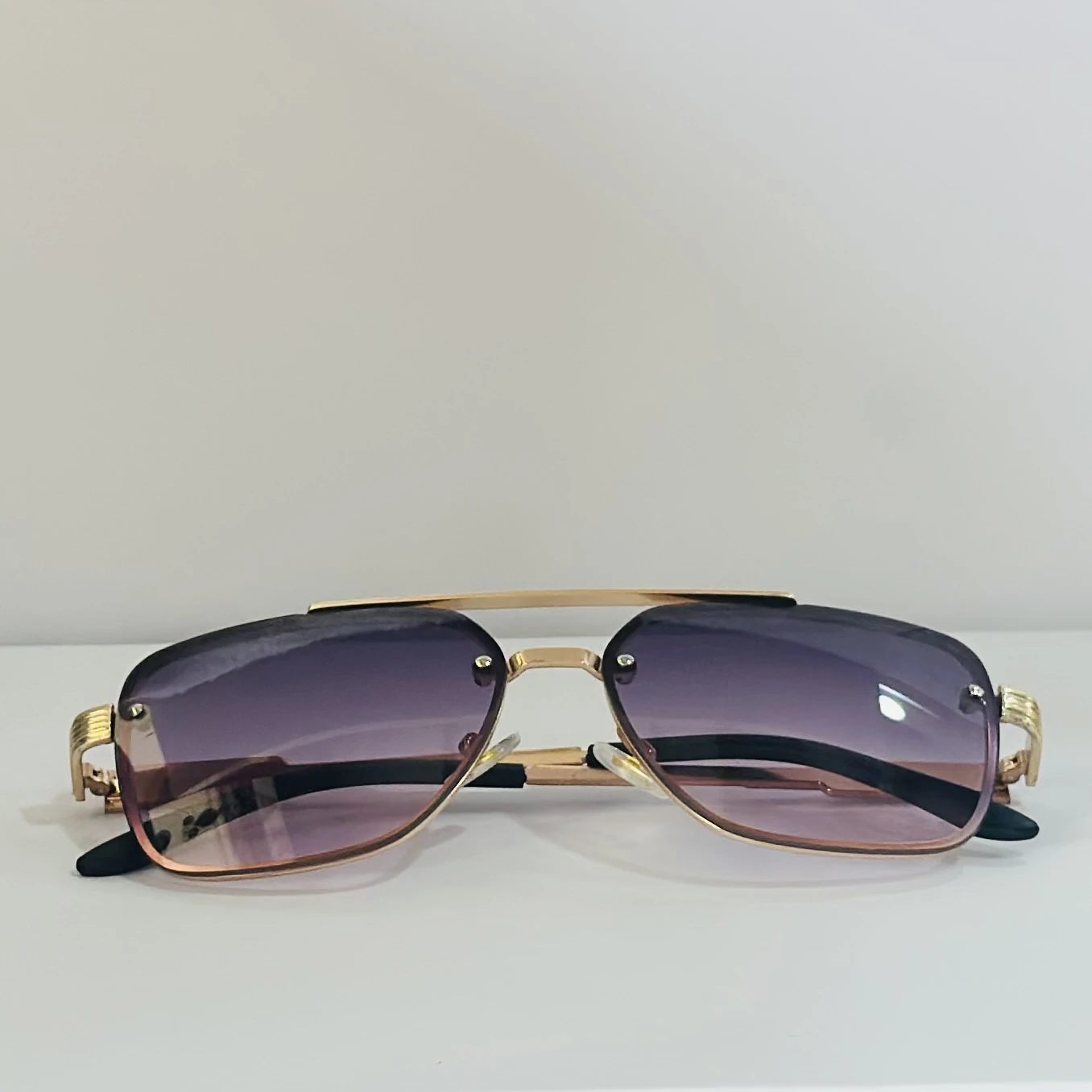 pair of fashionable sunglasses with a gold frame and purple gradient lenses.