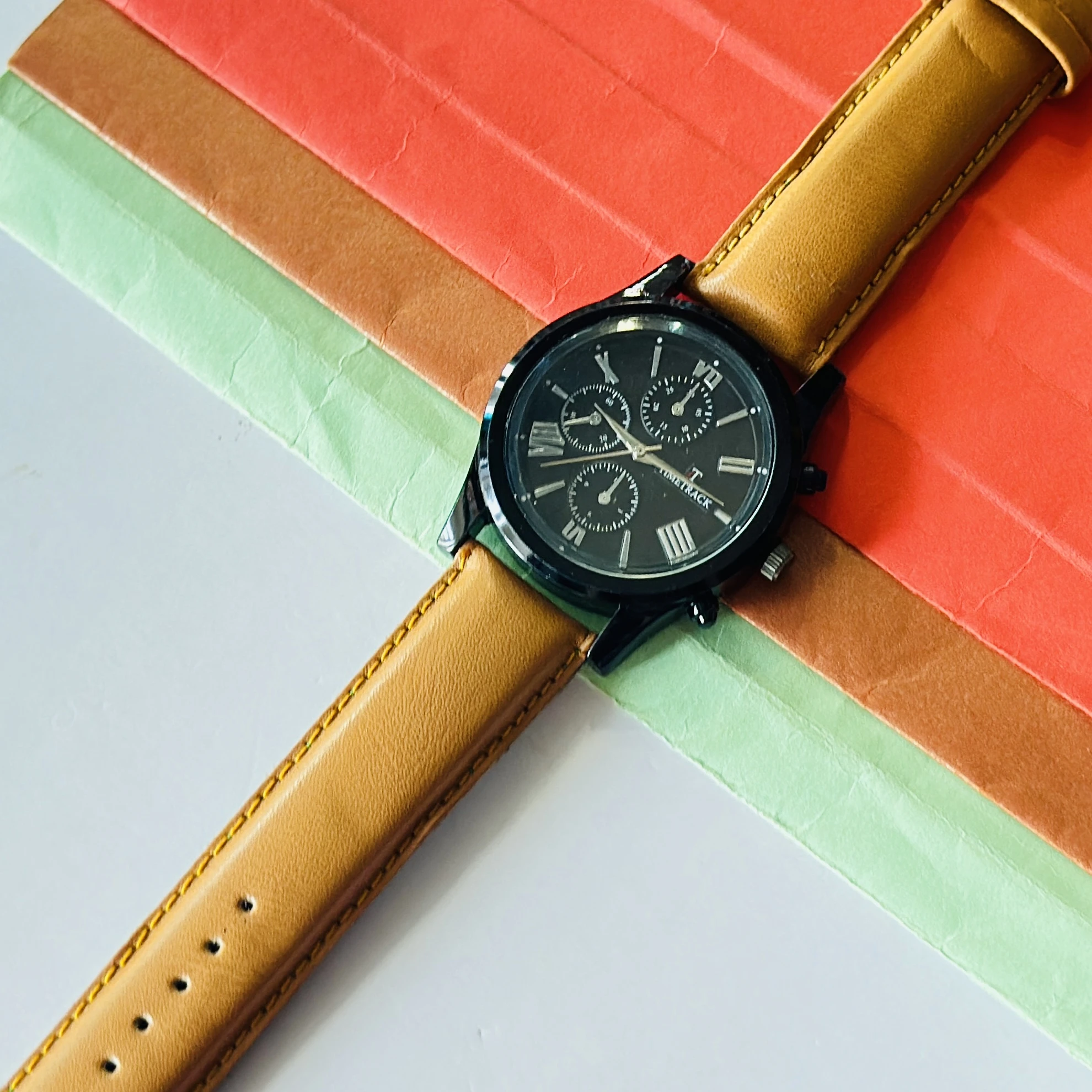 Timetrack quartz analog watch with a black dial and a brown leather strap.