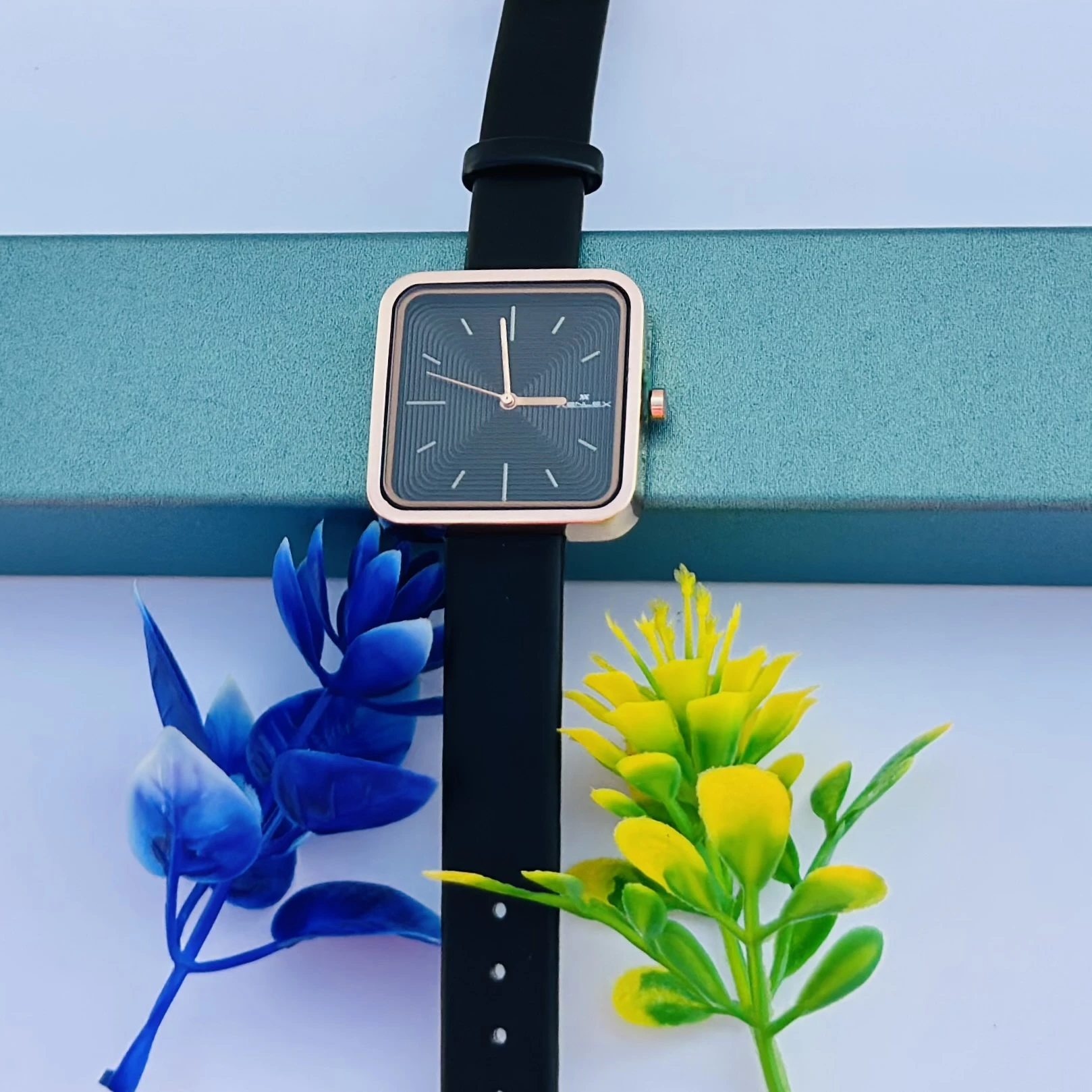 square-dial women's watch with a black strap and rose gold-tone case.