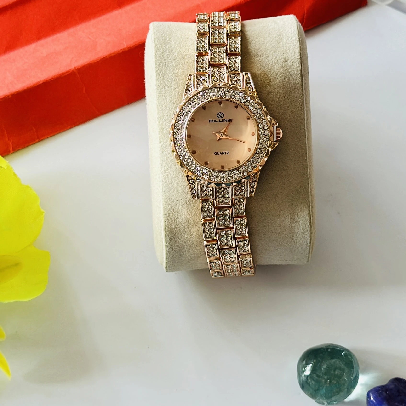 Riluns branded quartz watch featuring a rose gold finish and rhinestone embellishments.