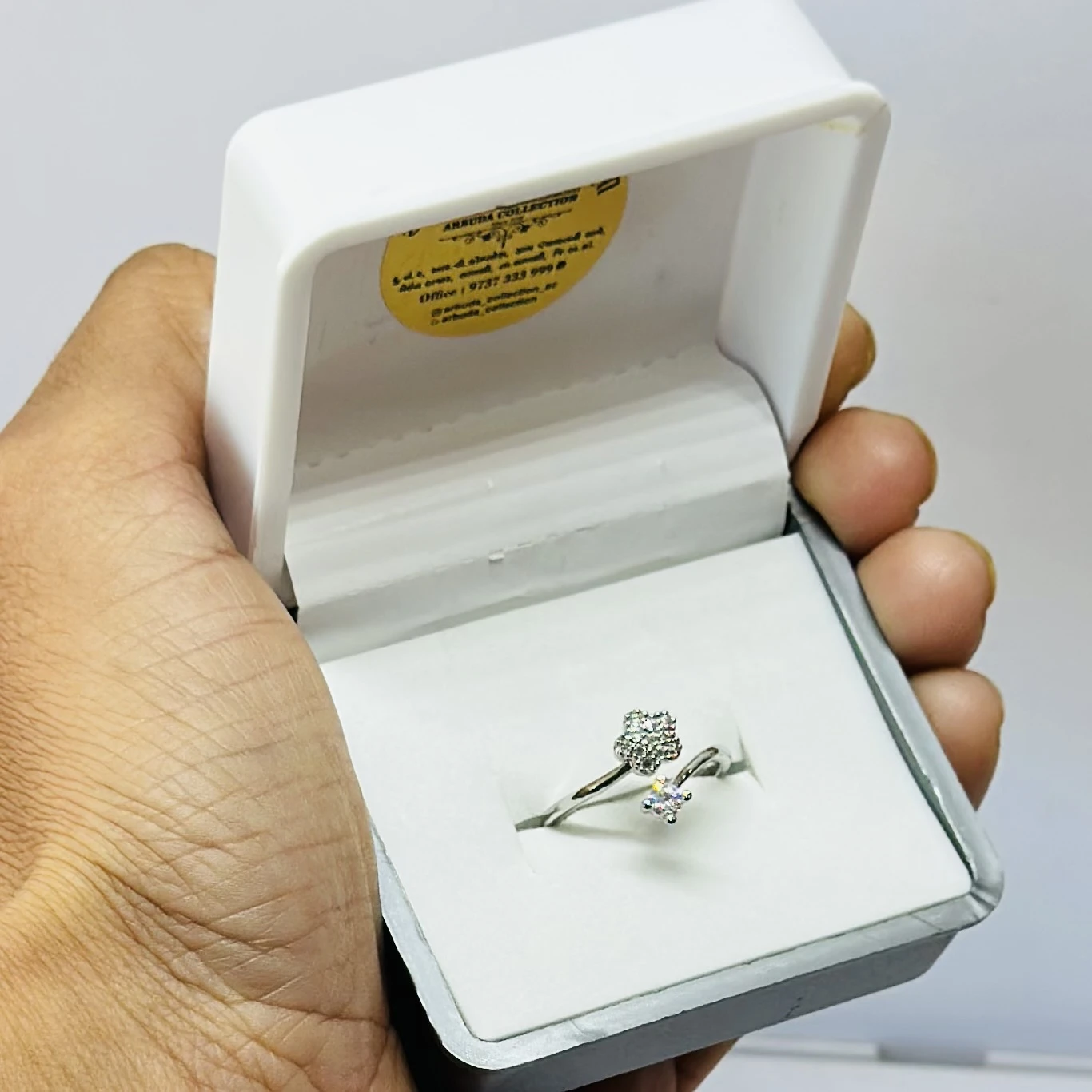 an adjustable silver-toned, stone-studded finger ring with a flower design.