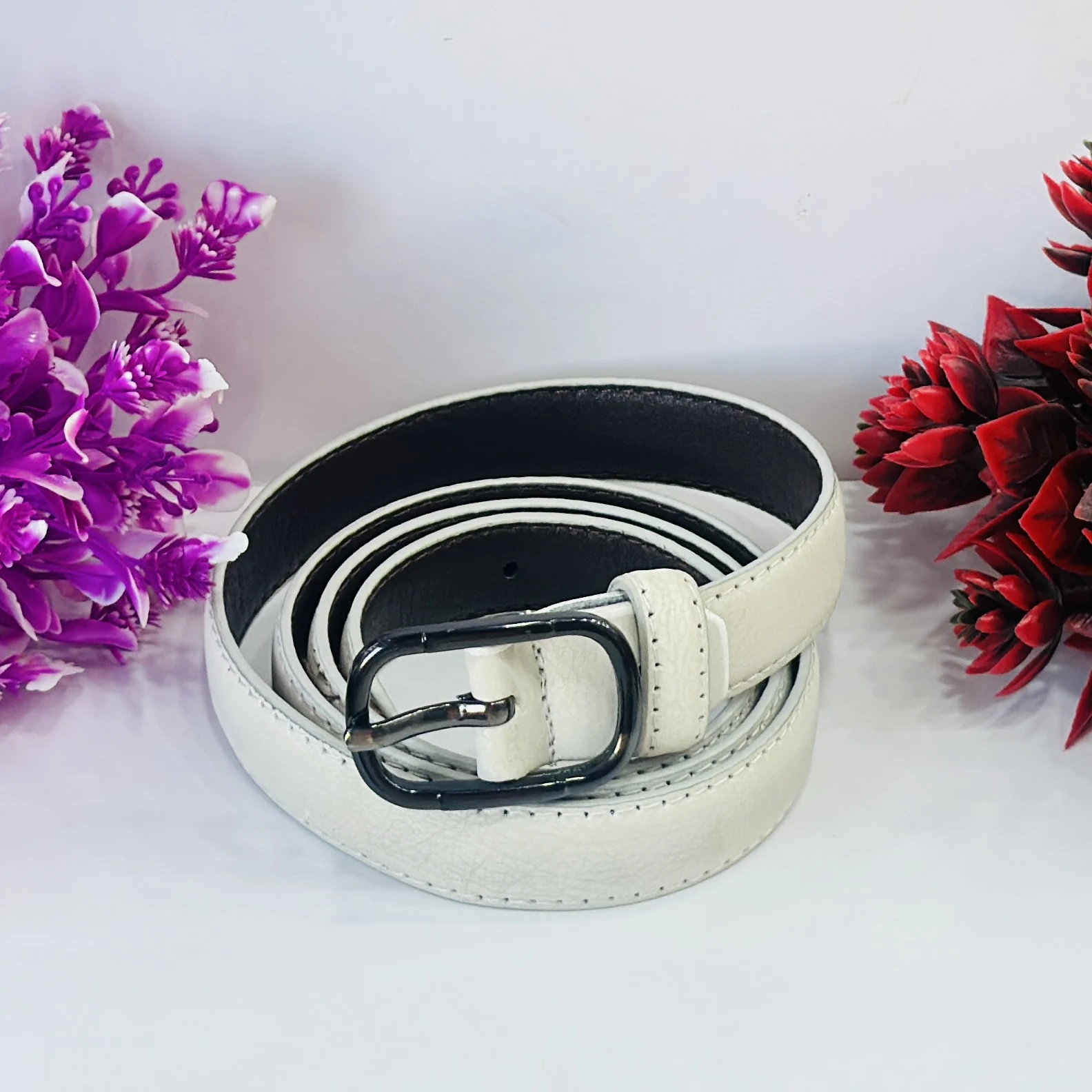 white leather women's belt with a black buckle.