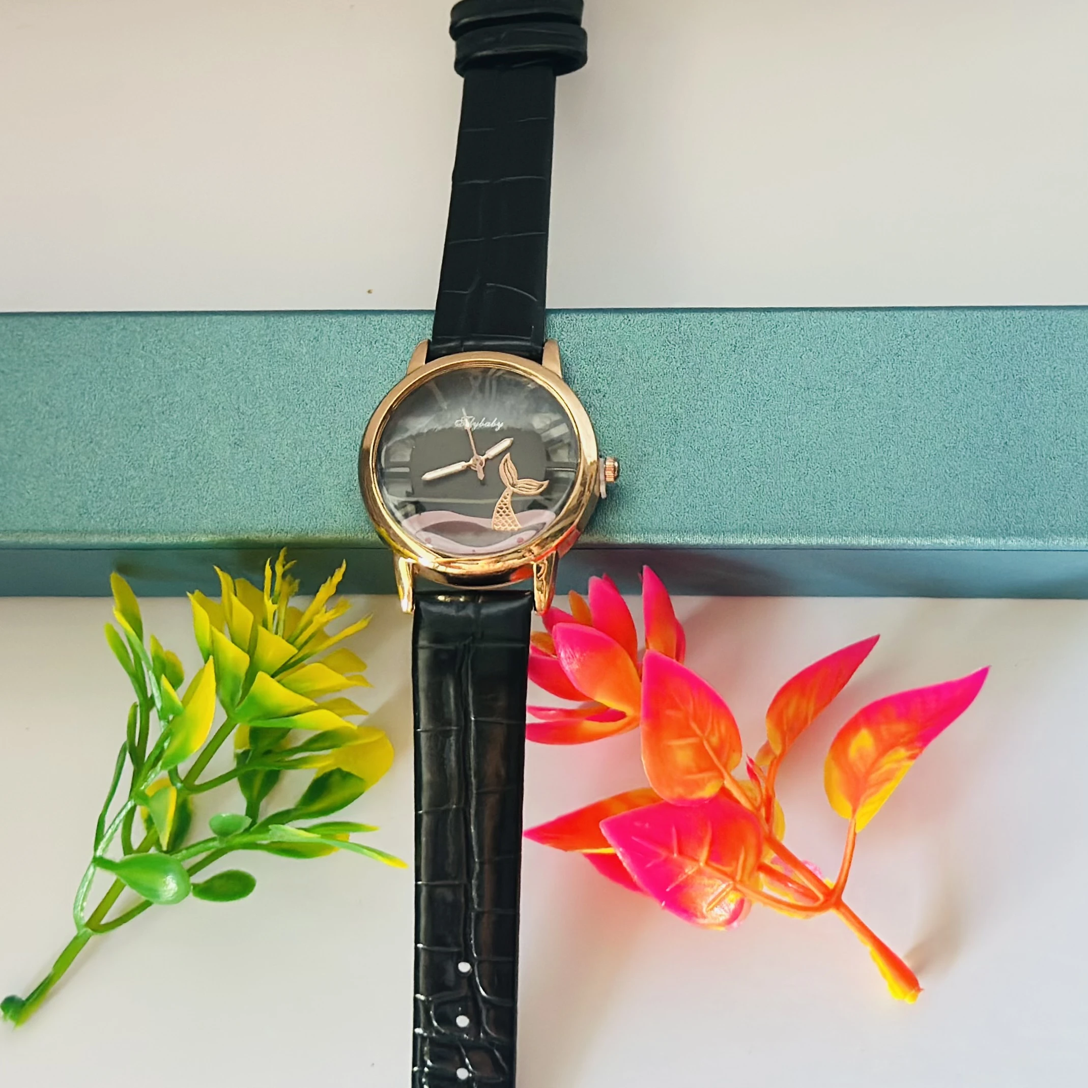 gold-toned analog watch with a black strap and a whale tail design on the dial.