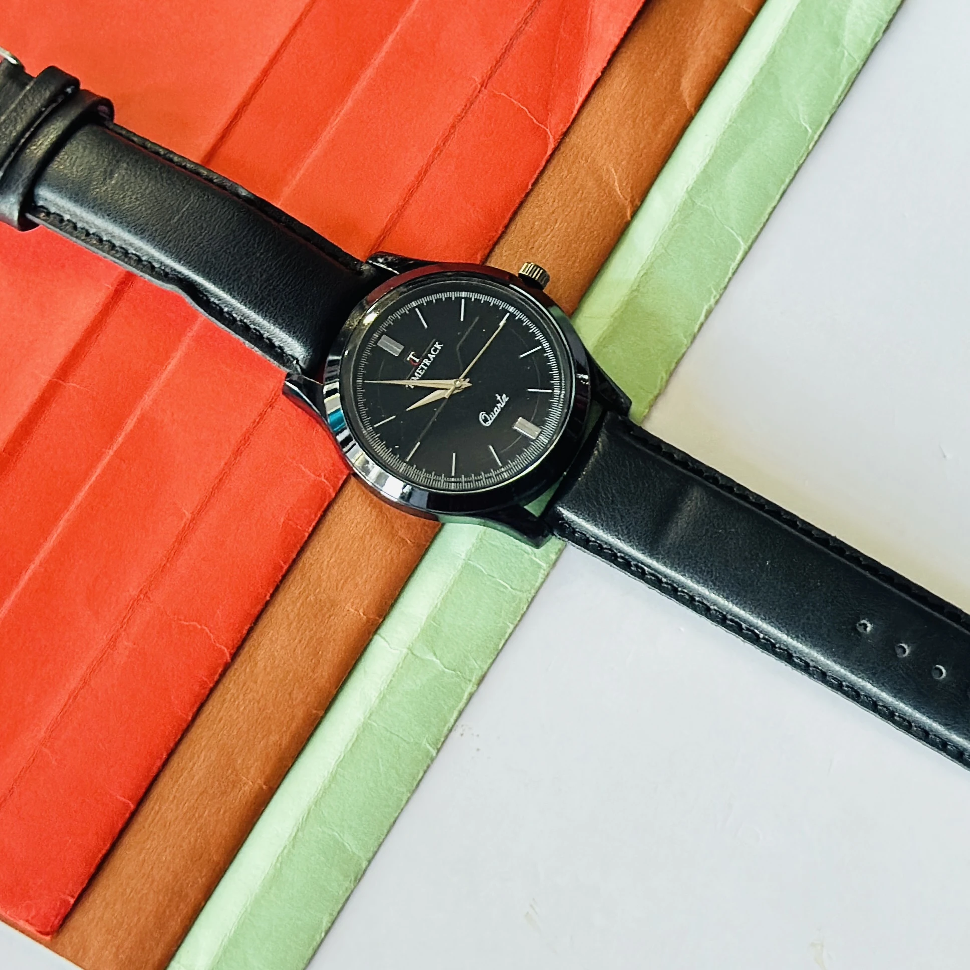 Timetrack Quartz wristwatch features a black analog dial and a black leather strap.