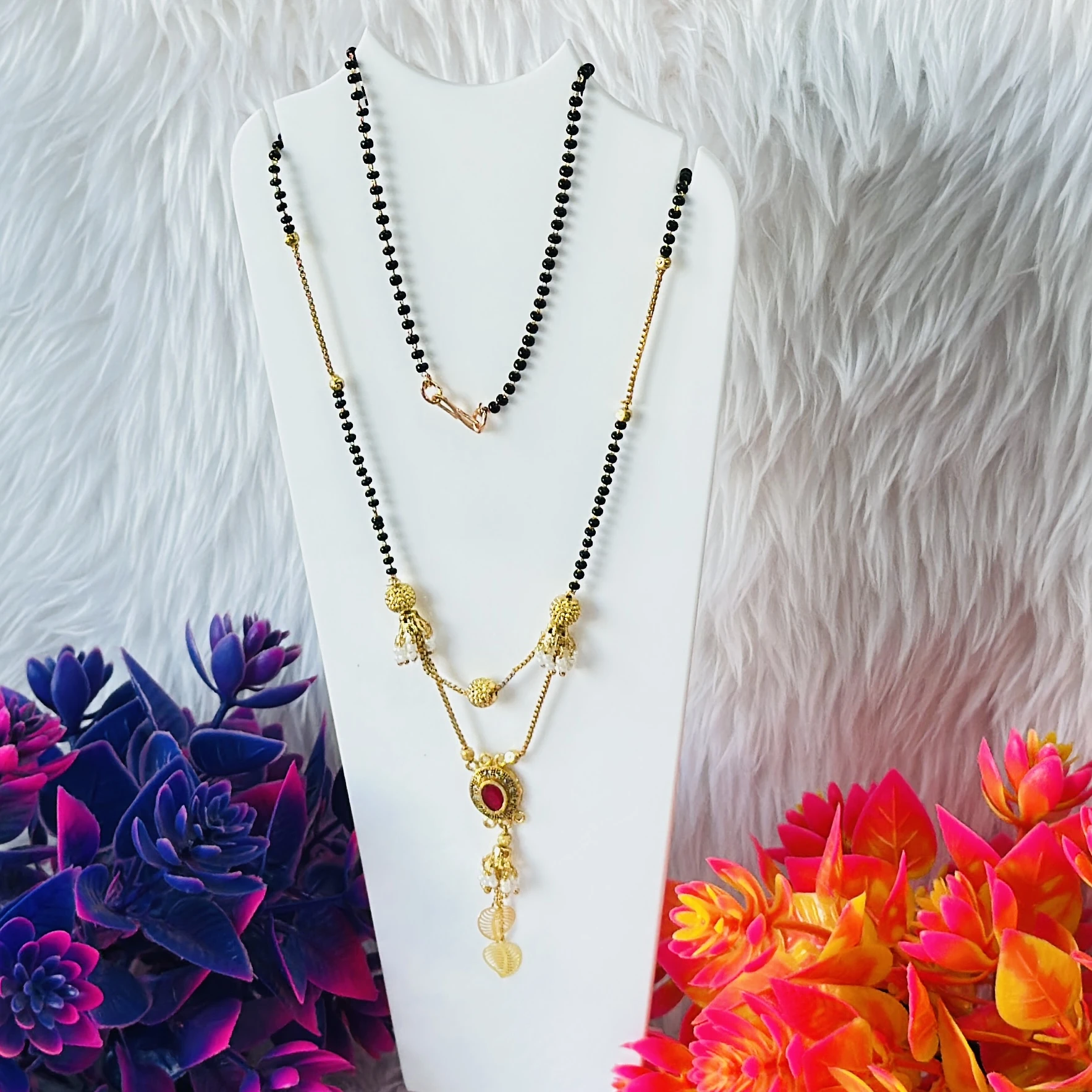 gold-plated mangalsutra with black beads and a red stone pendant.