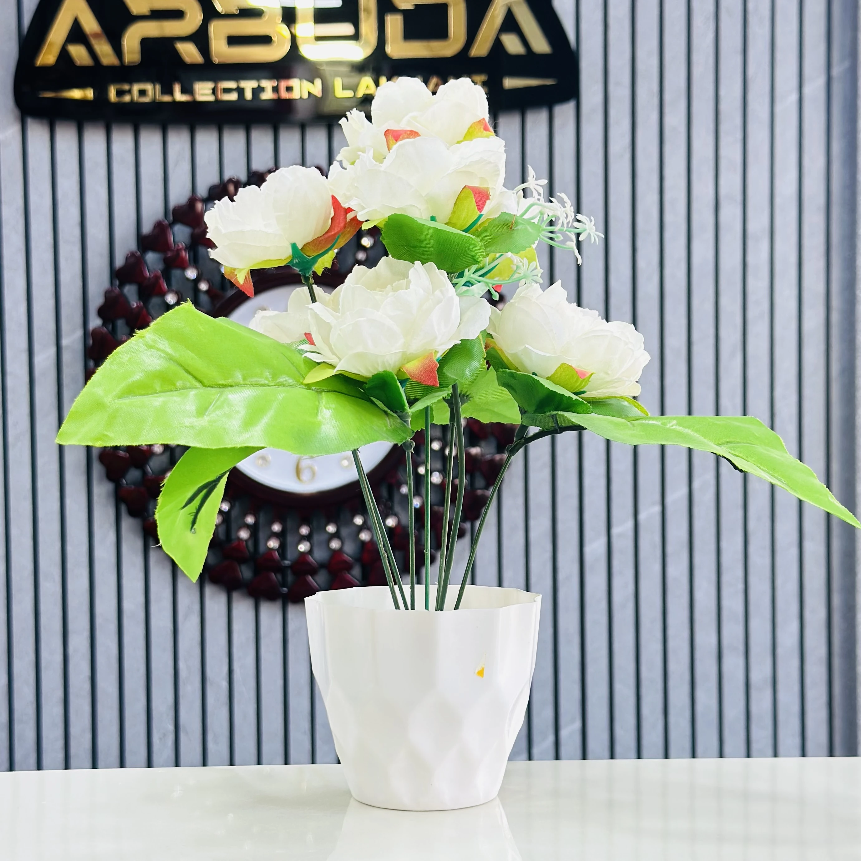 Lotus flower arrangement in a white geometric pot.
