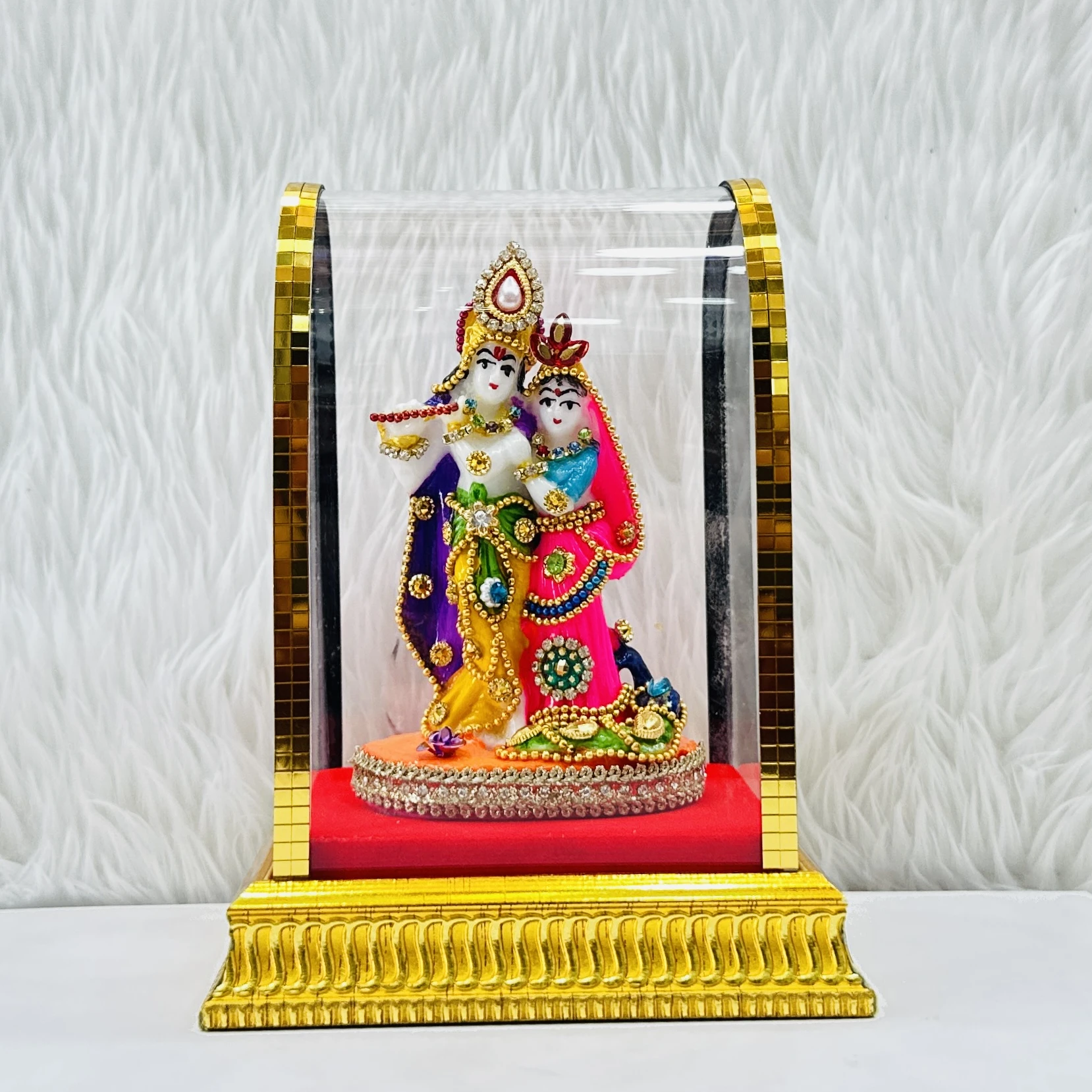 Radha Krishna statue enclosed in a protective glass case.
