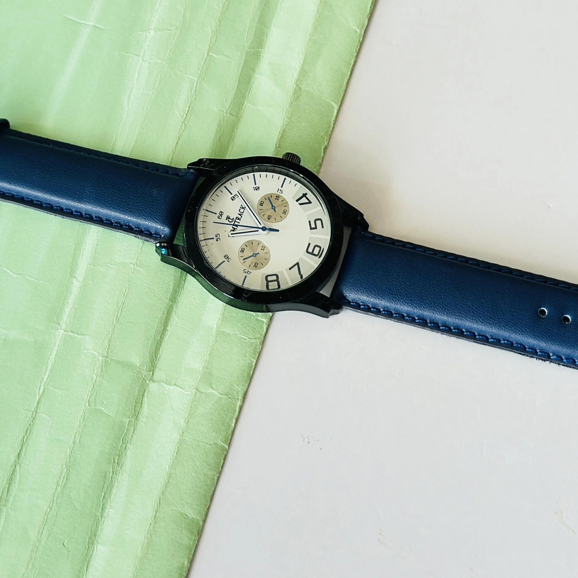 METRACK brand analog watch with a blue leather strap and a white dial