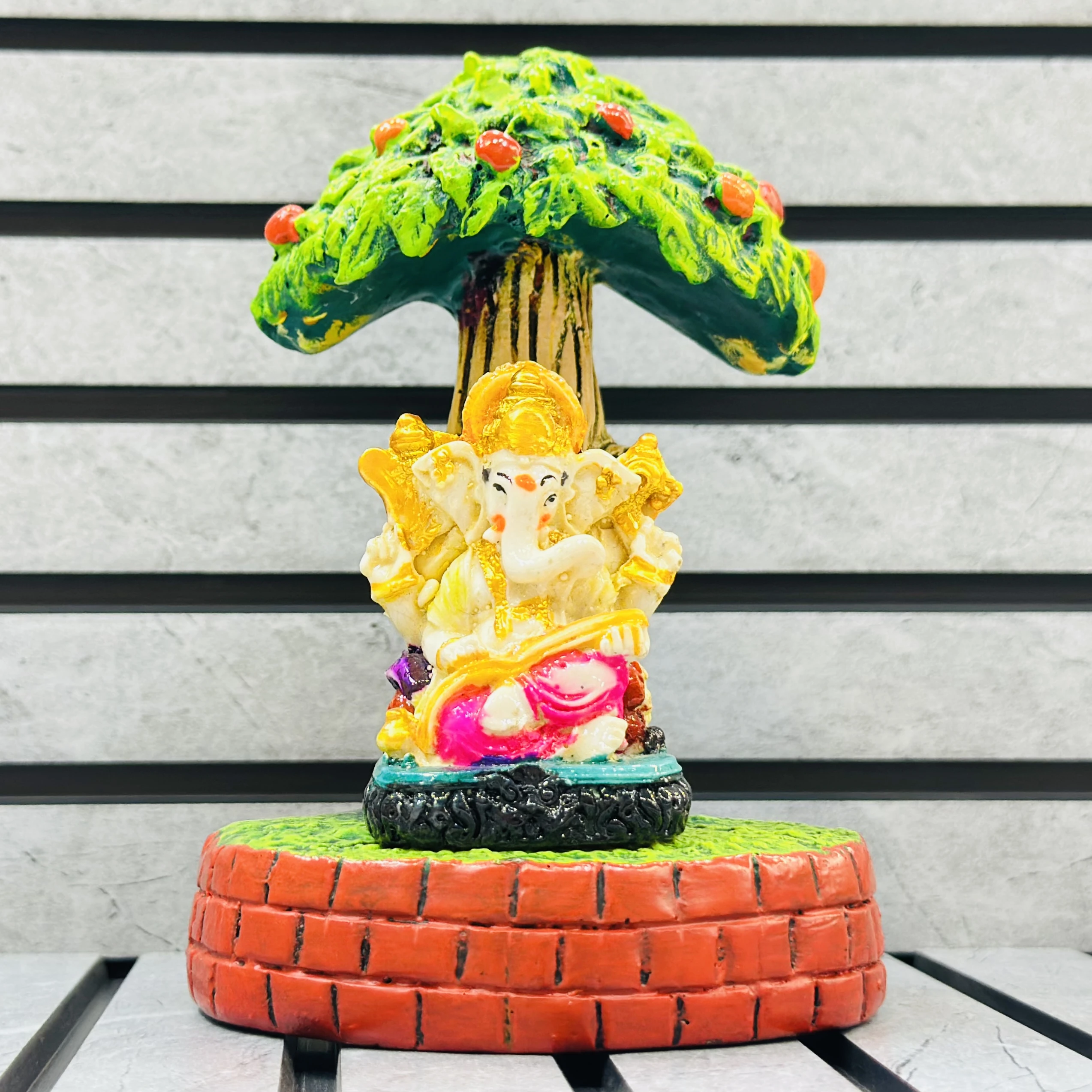 small statue of the Hindu deity Lord Ganesha seated under a tree