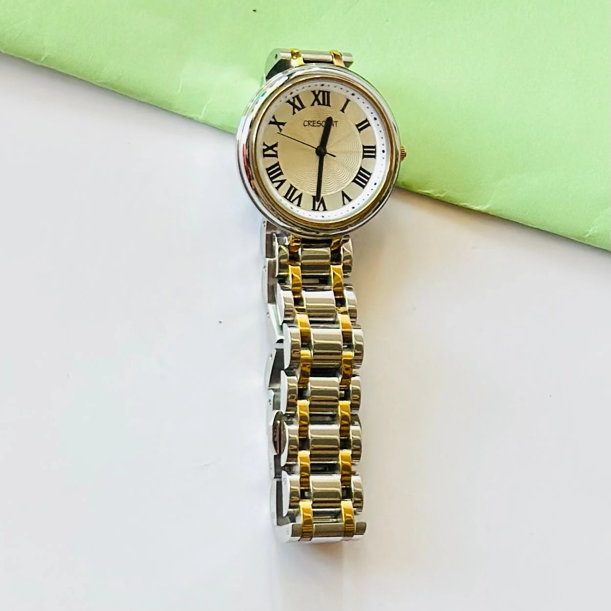 Crescent analog watch with a rectangular case and a two-tone (silver and gold) metal bracelet.