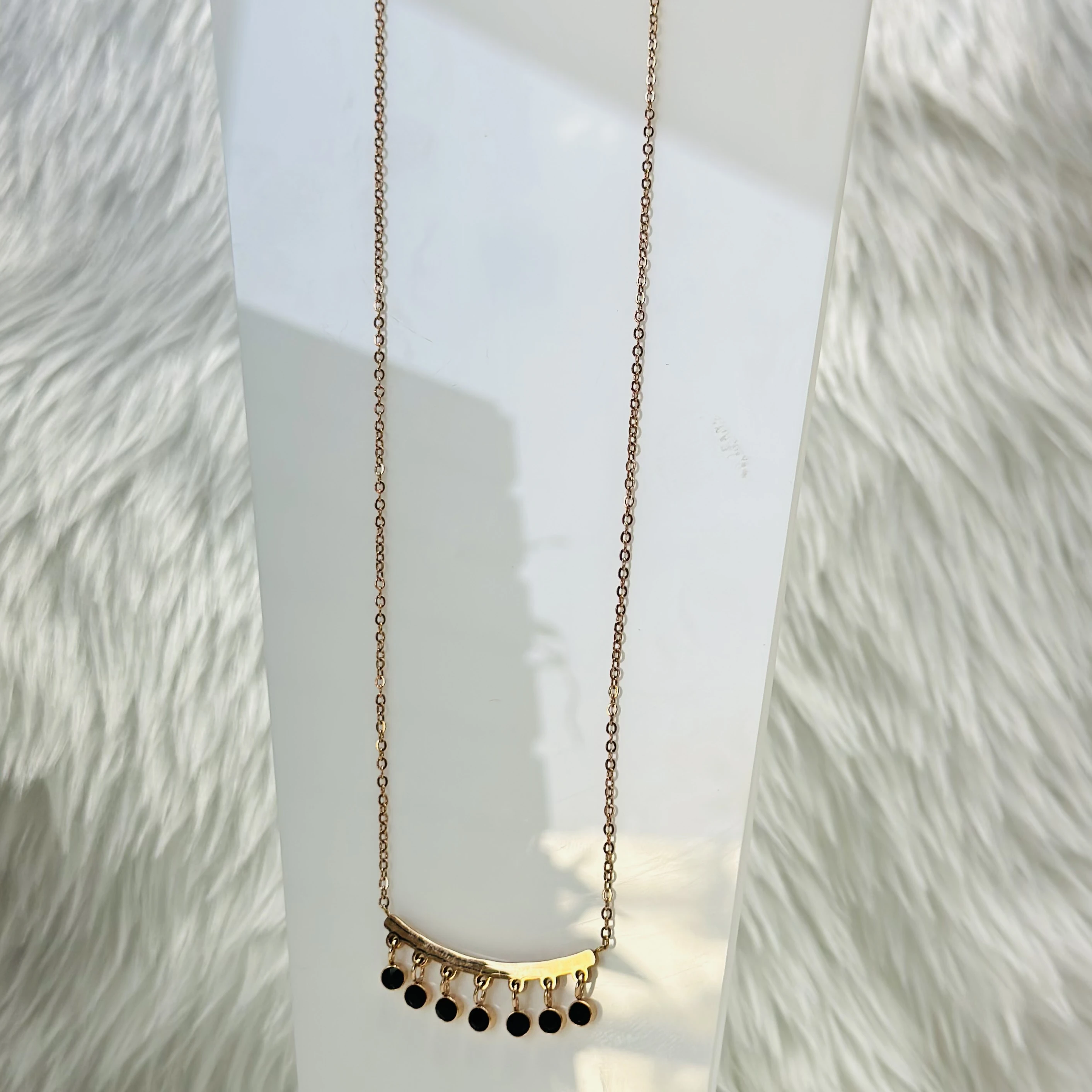 Mangalsutra necklace with a curved bar pendant and black beads.