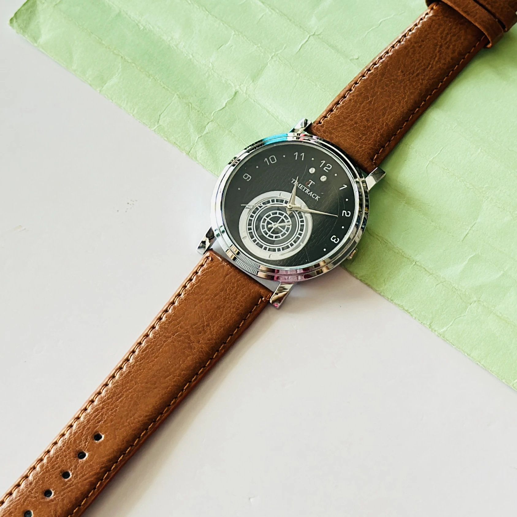 quartz analog watch with a brown leather strap and a black dial
