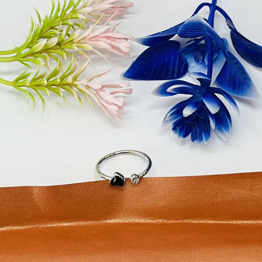 An adjustable silver-toned ring with a black heart and a clear stone accent.