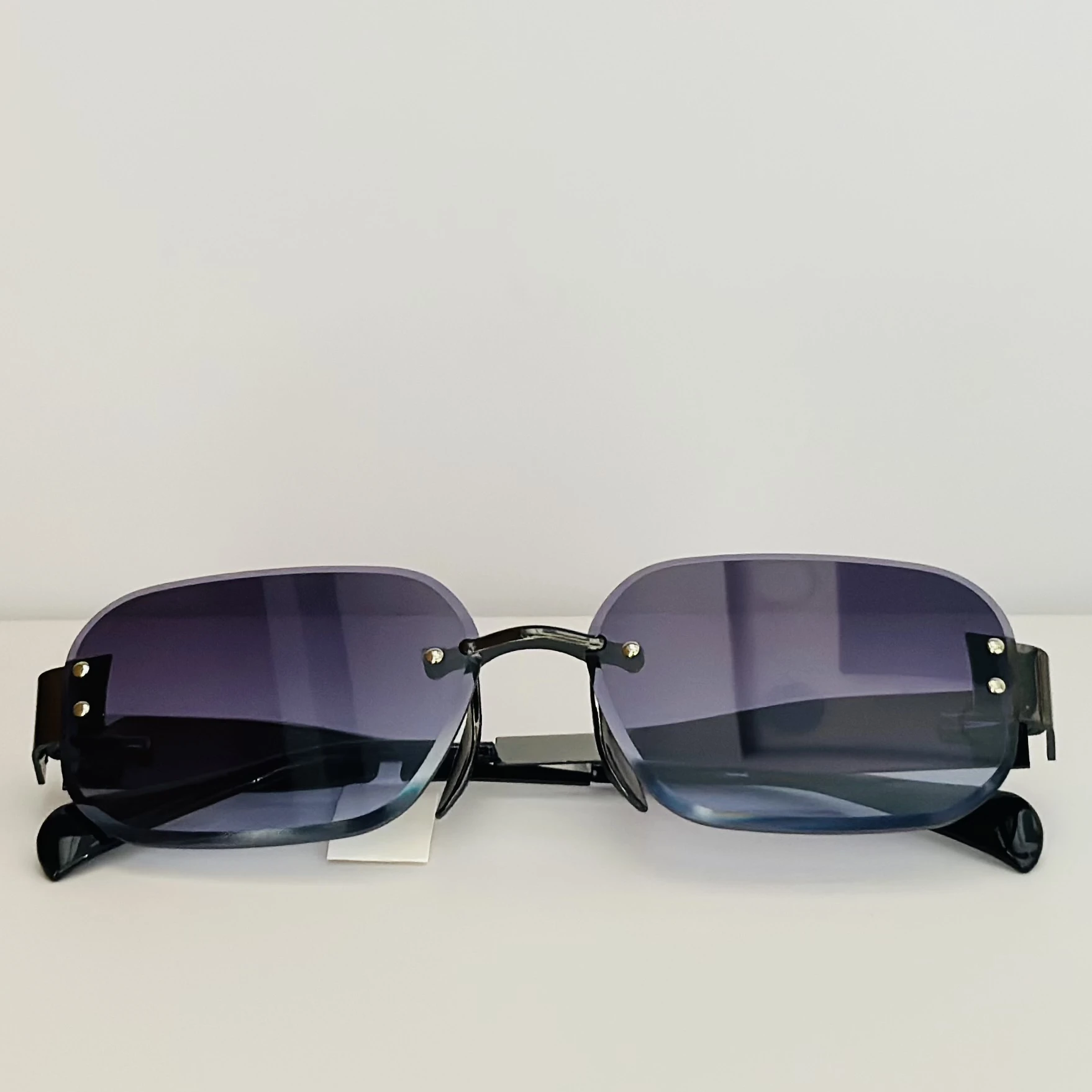 Frameless cut-edge sunglasses with black temples and a gradient tint.