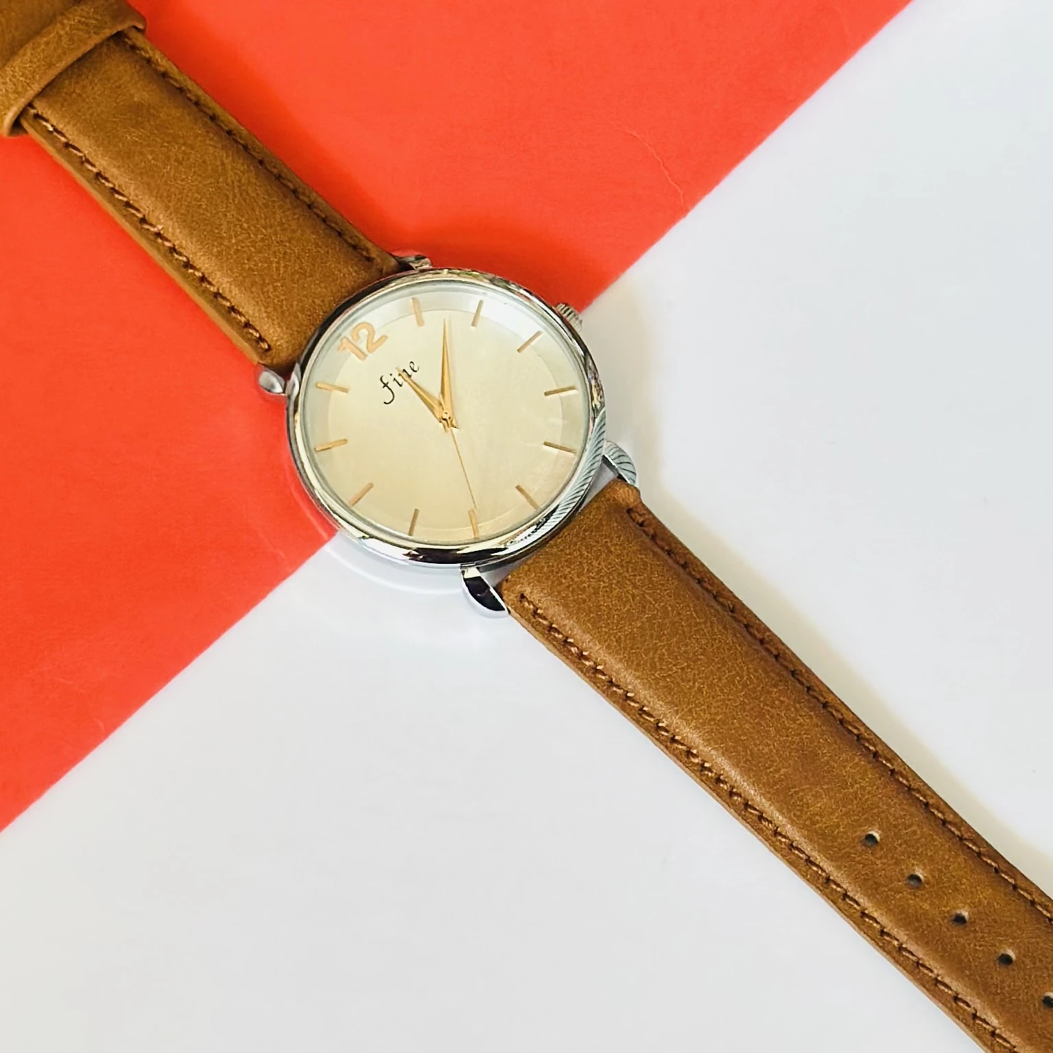 minimalist analog watch with a white dial, gold-tone case, and a brown leather strap