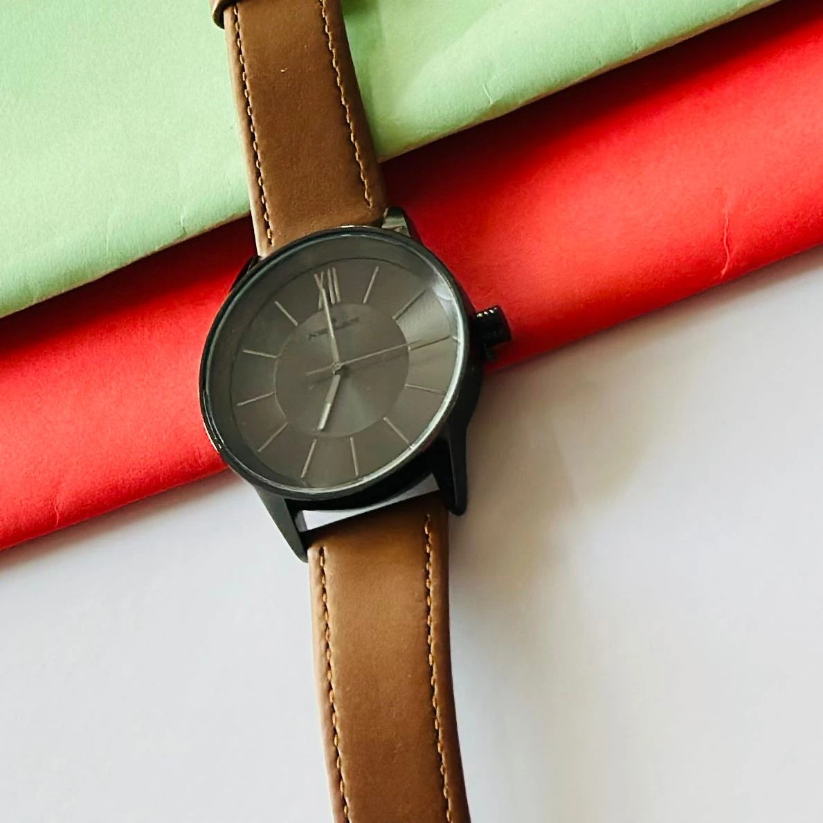 round analog watch with a brown leather strap