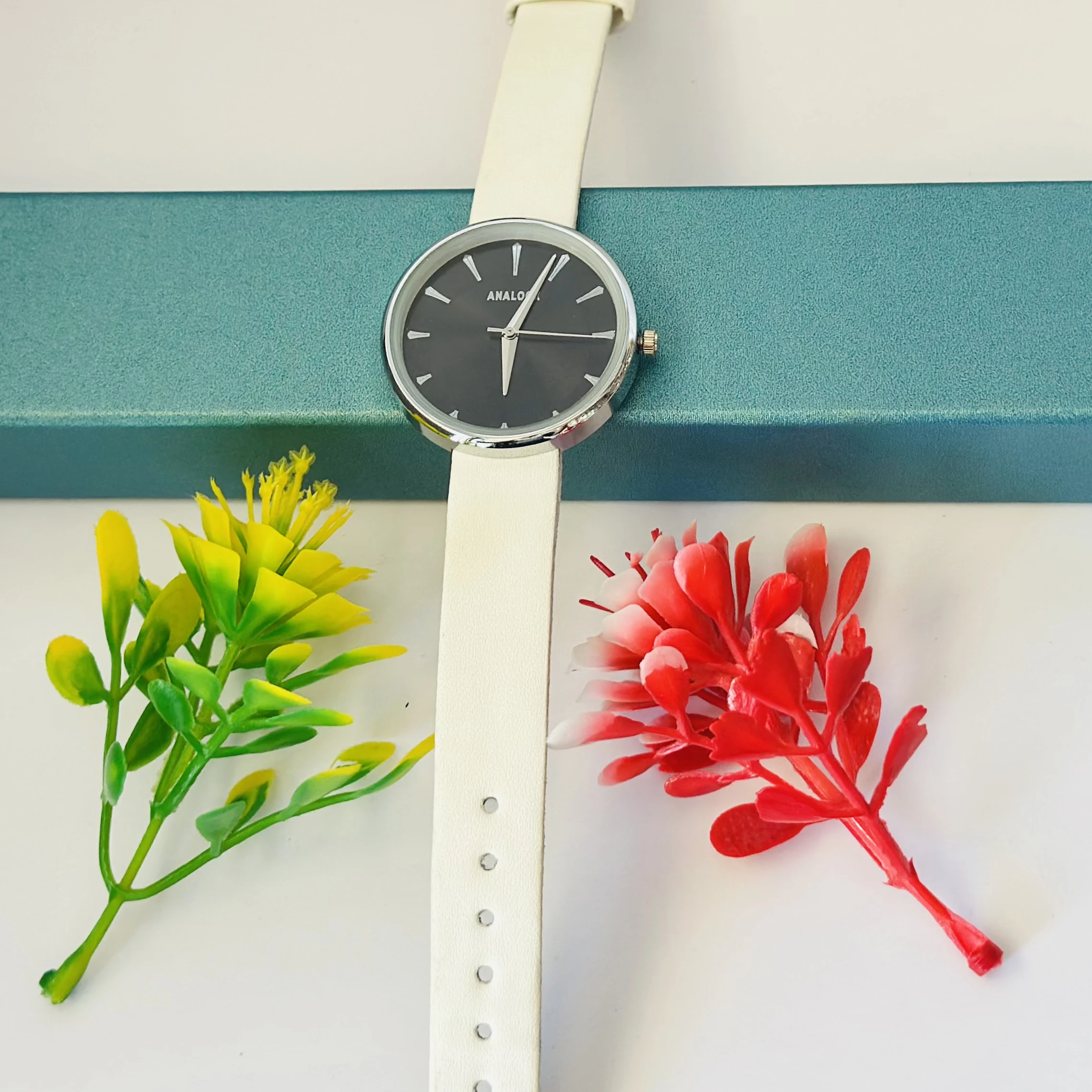 Analogue watch with a black face and a white band.