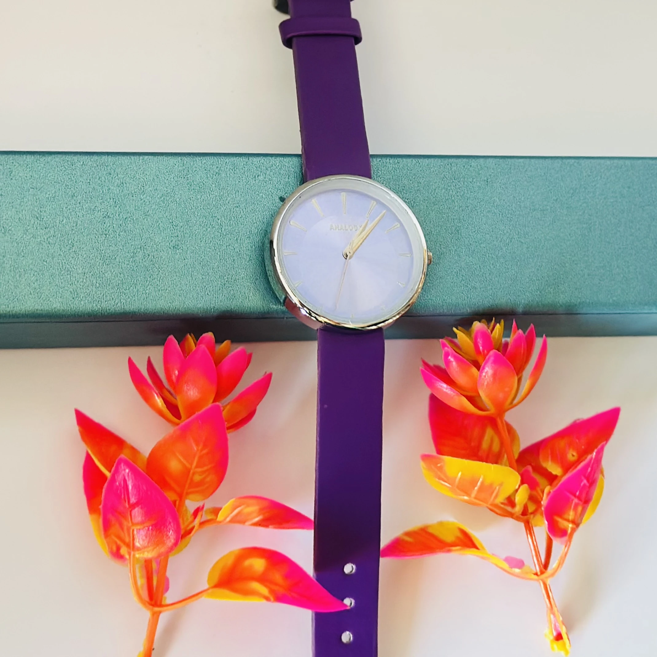 purple analog watch with a black leather strap.