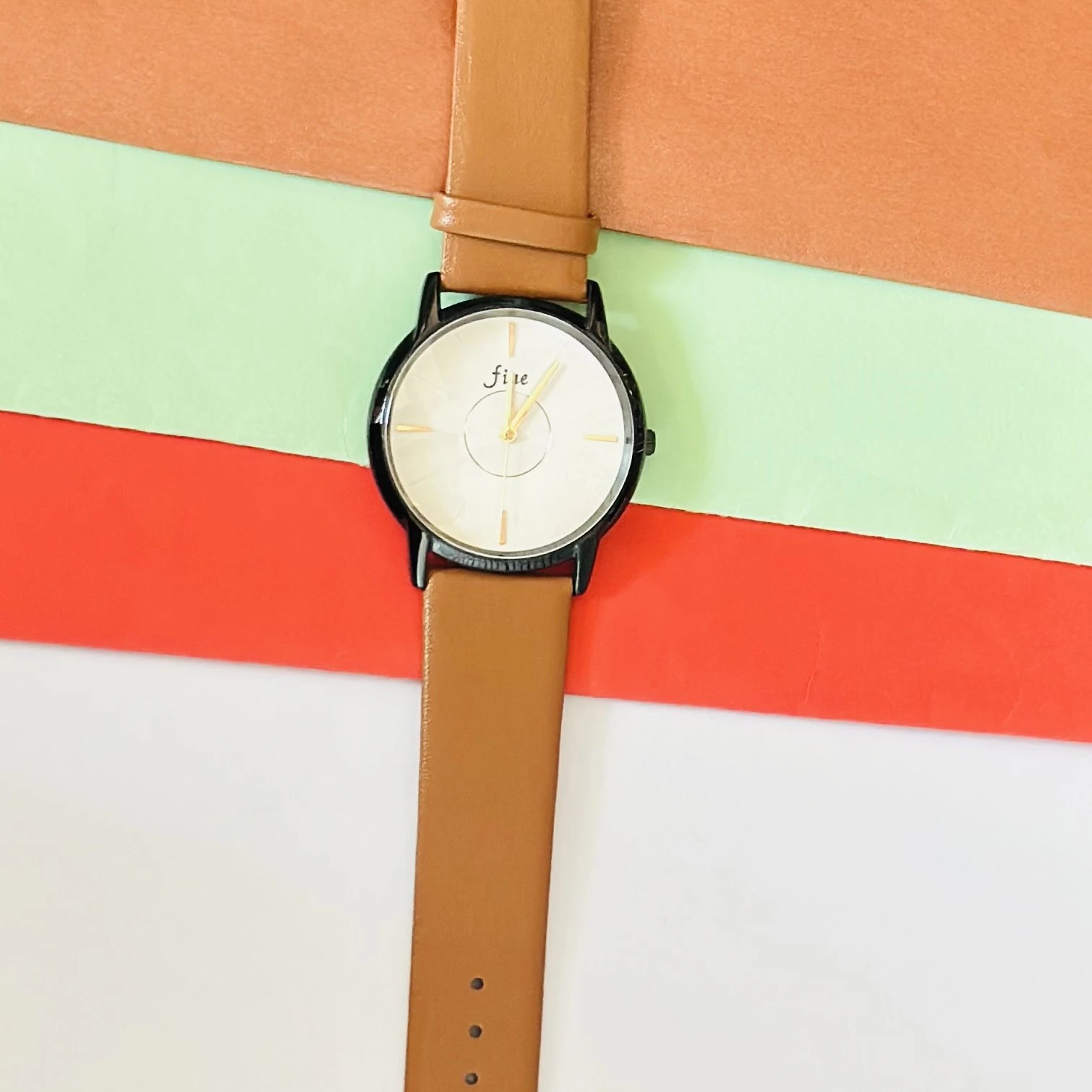 Analog wrist watch with a brown leather strap.