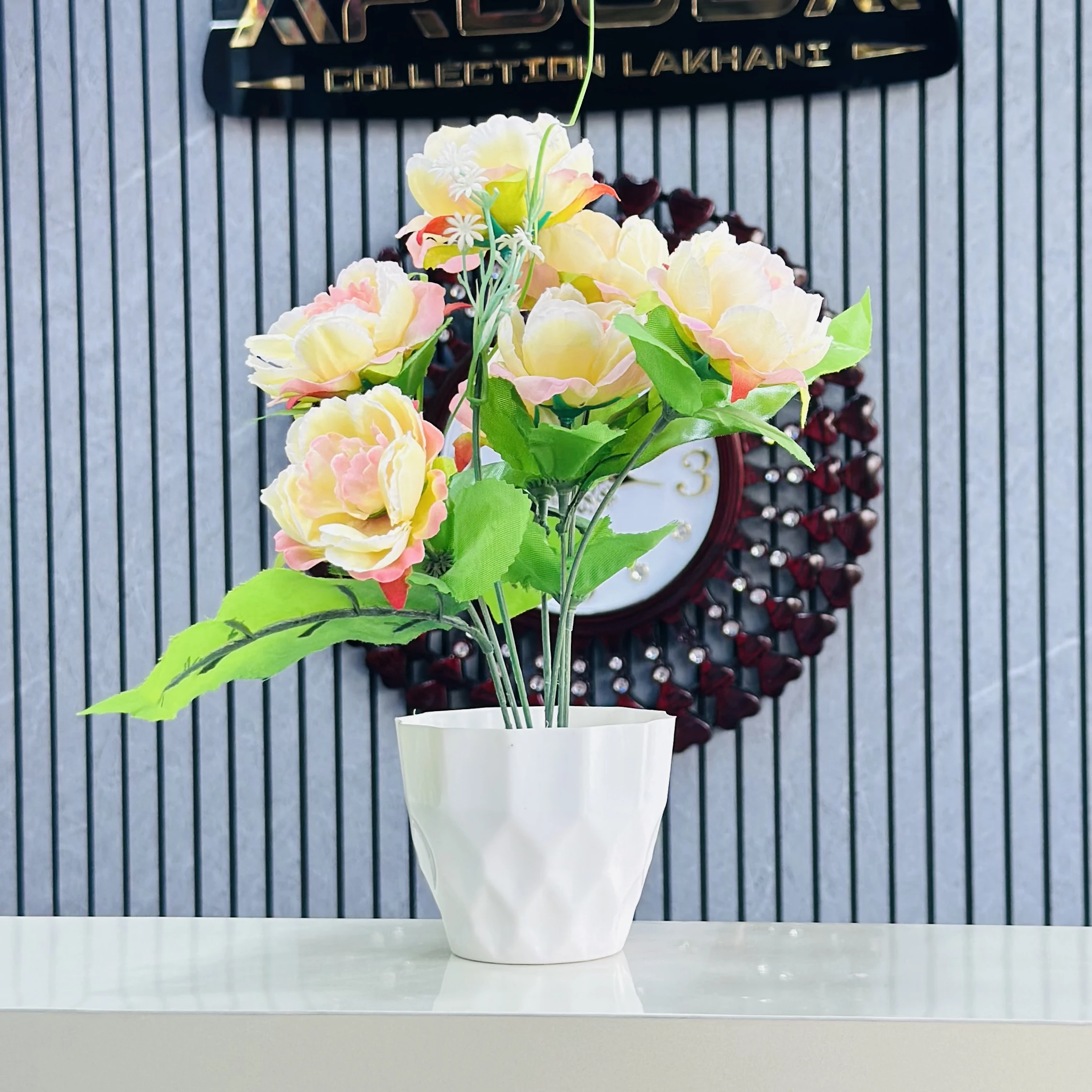 An artificial flower arrangement in a white ceramic pot.