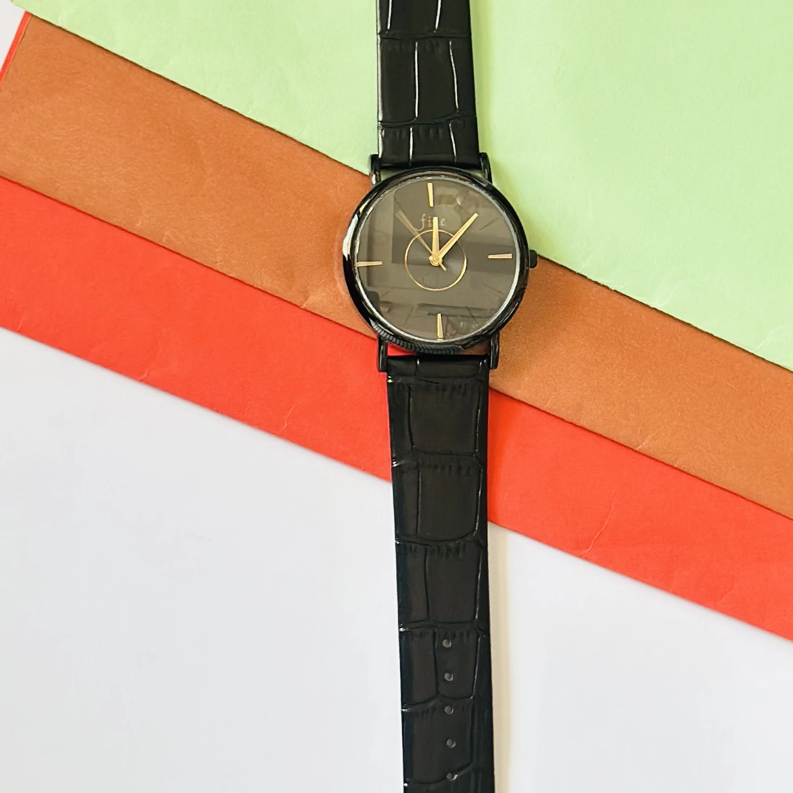 Black analog watch with a black textured leather-style strap.