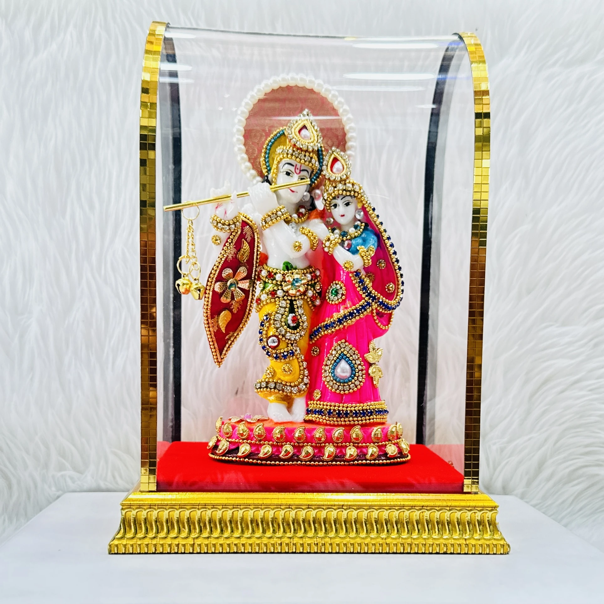 Radha Krishna statue enclosed in a protective glass dome.