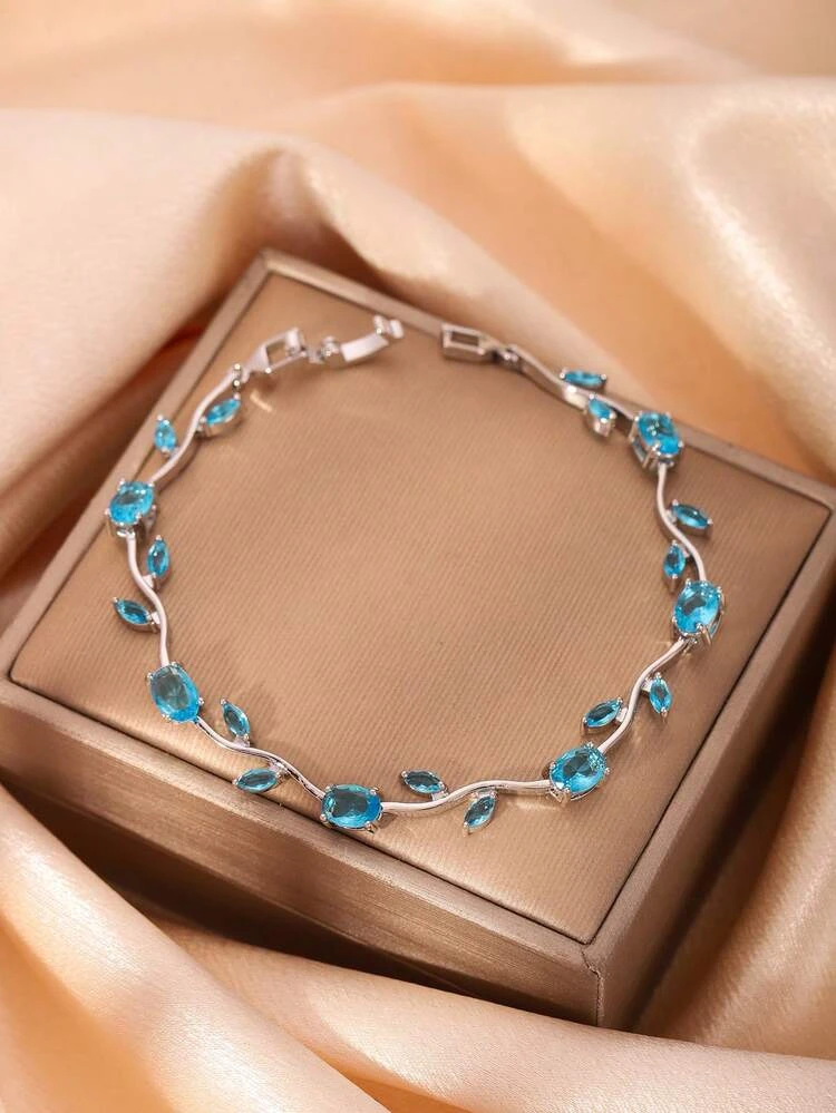 silver-toned bracelet features sparkling blue stones arranged in a delicate floral or vine-like pattern