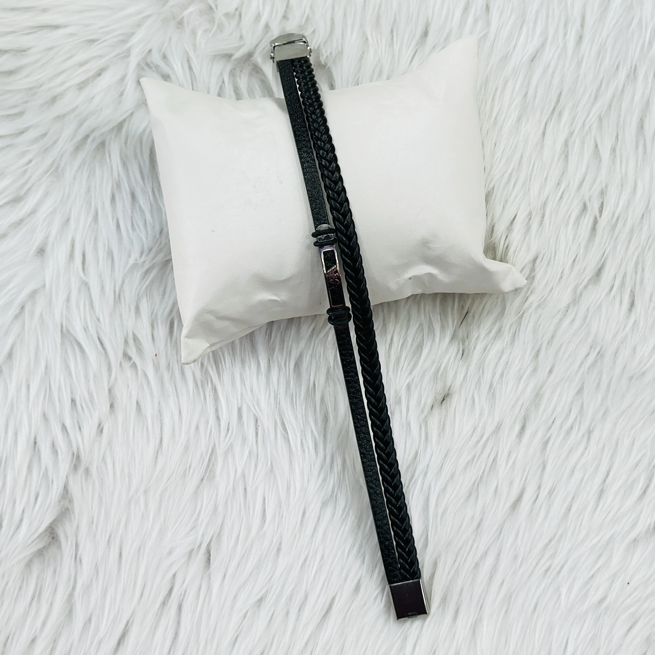 Jewelry bracelet features a black leather design paired with a stainless steel bar.