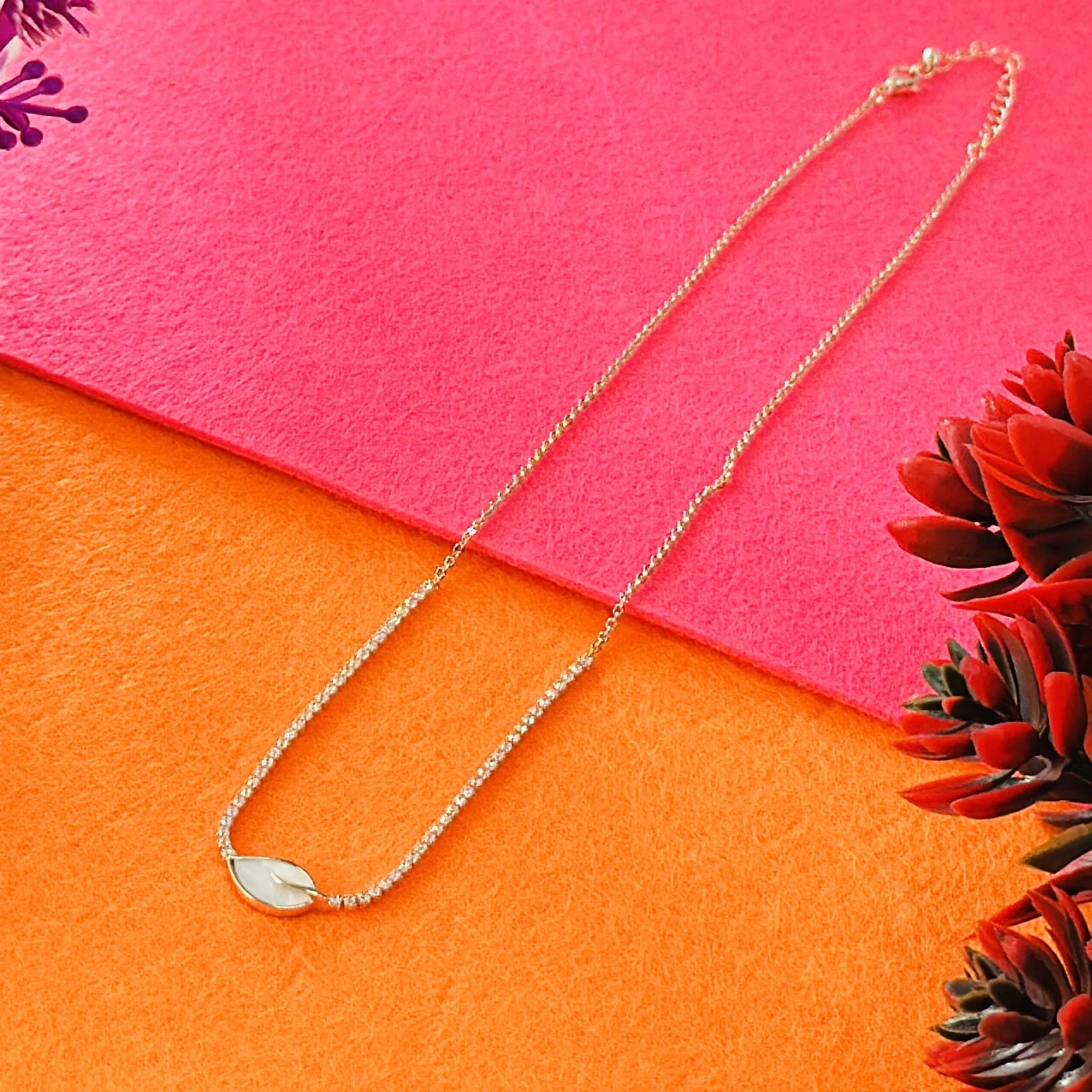 Gold plated chain necklace with a leaf-shaped white pendant.
