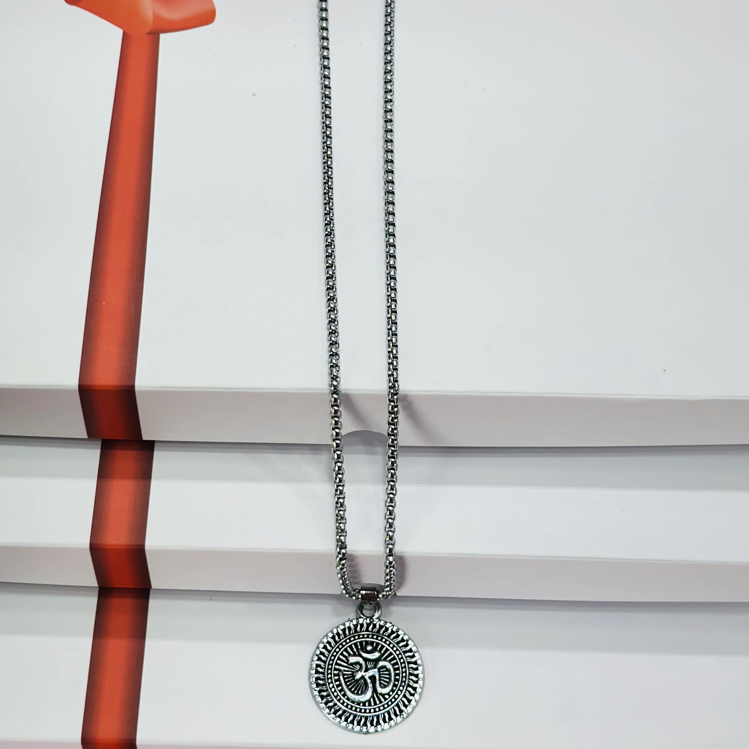 Silver toned metal necklace featuring an Om symbol pendant.