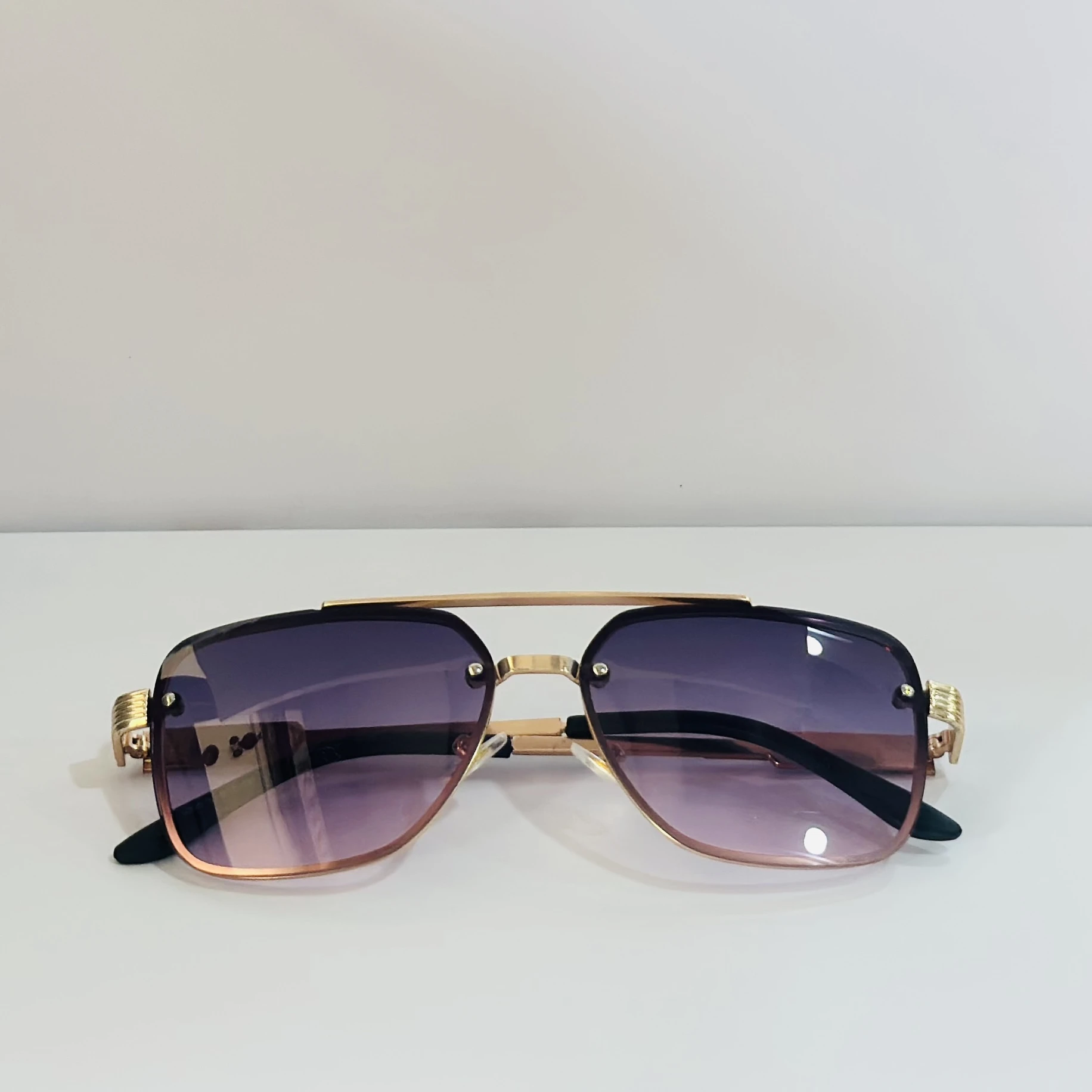 pair of fashionable sunglasses with a gold frame and purple gradient lenses.