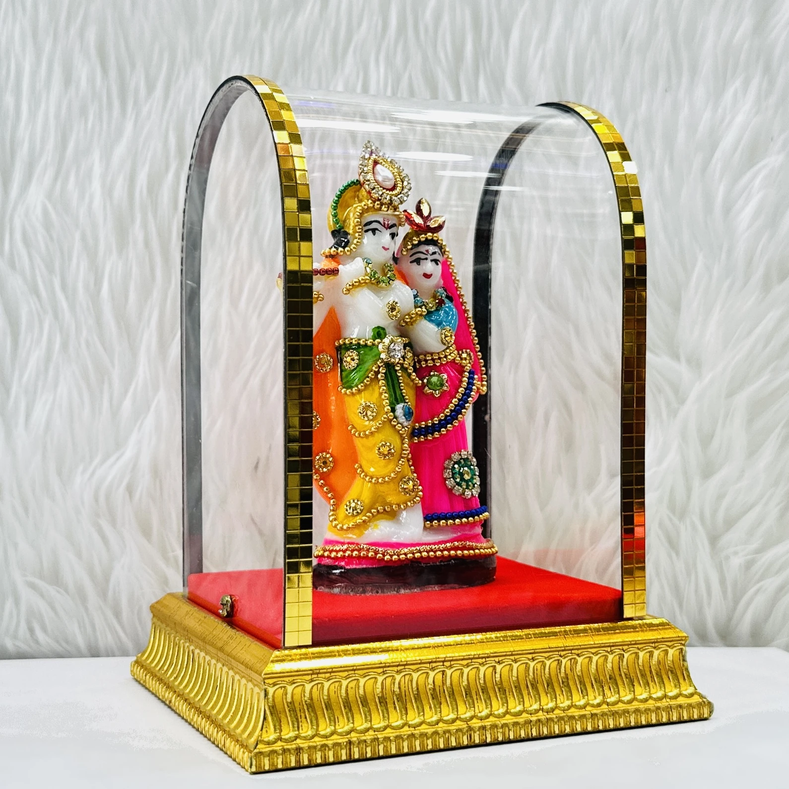 Radha Krishna statue enclosed in a protective glass case.