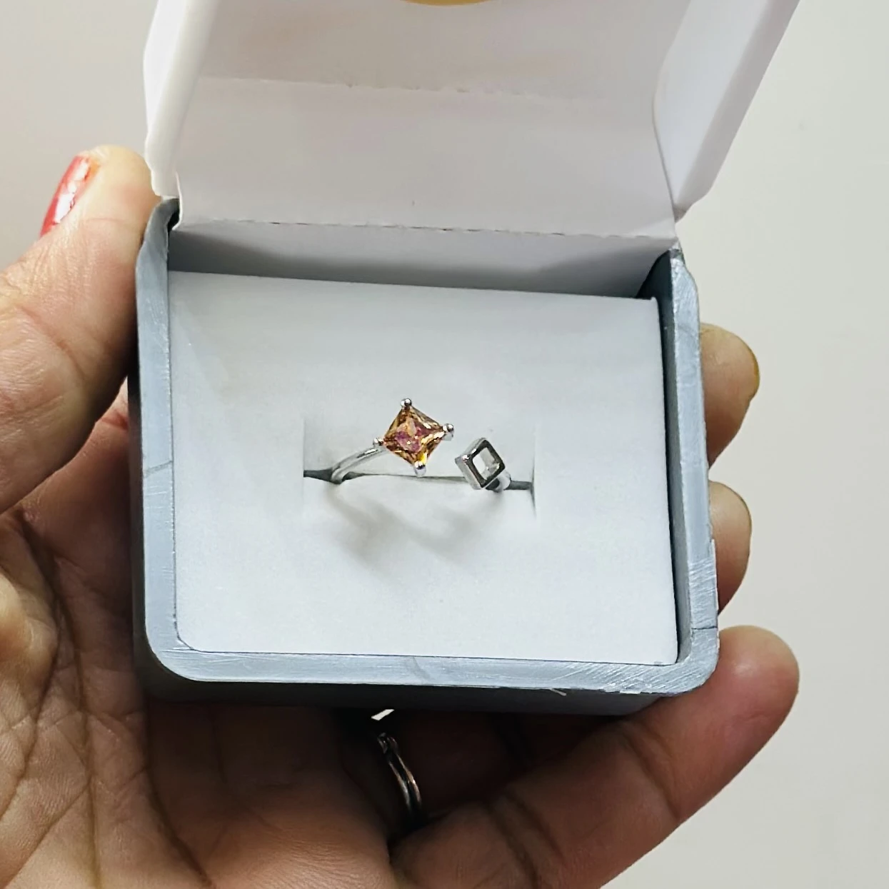 silver-plated, size-adjustable ring featuring an orange cubic zirconia stone.