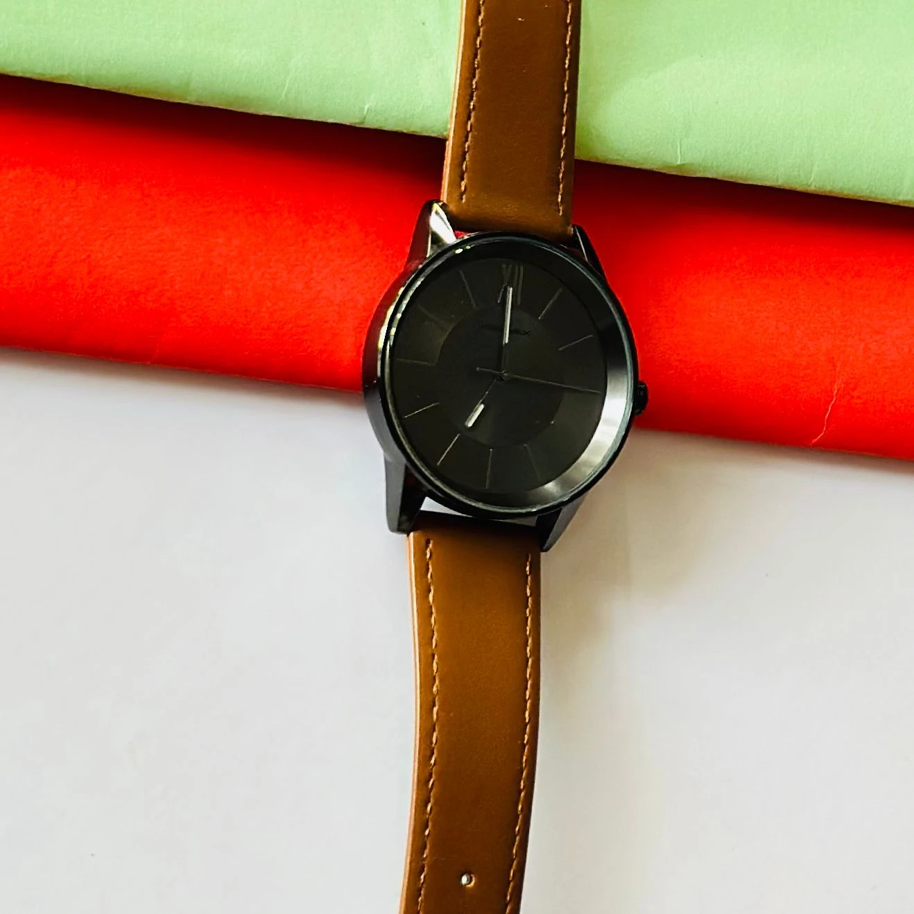 round analog watch with a brown leather strap