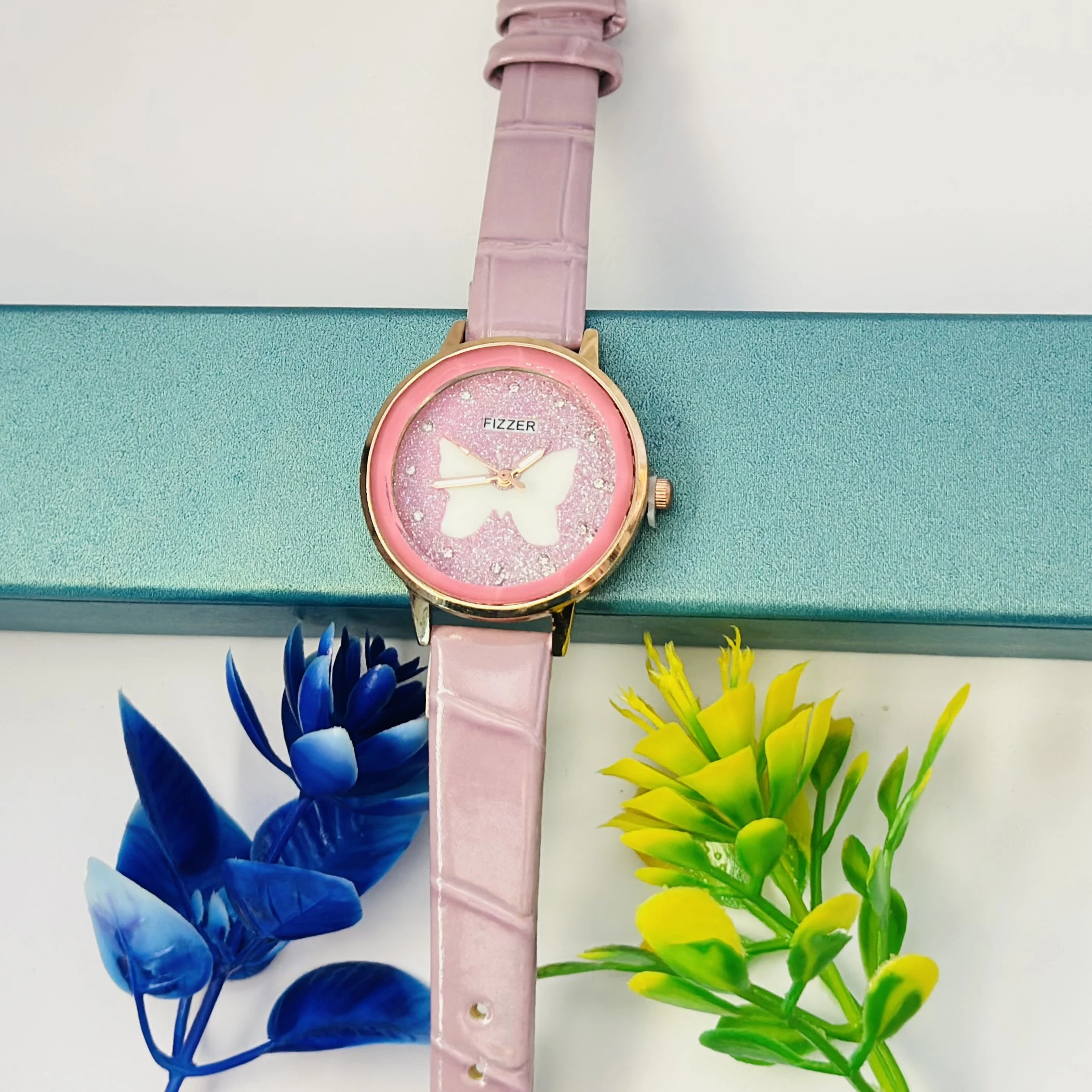Pink analog watch with a butterfly design and a leather-style strap.
