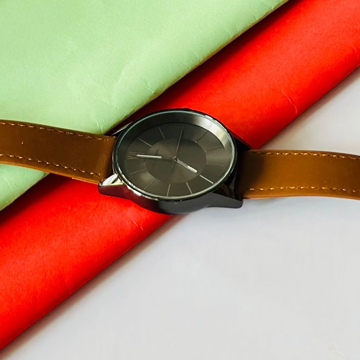 round analog watch with a brown leather strap