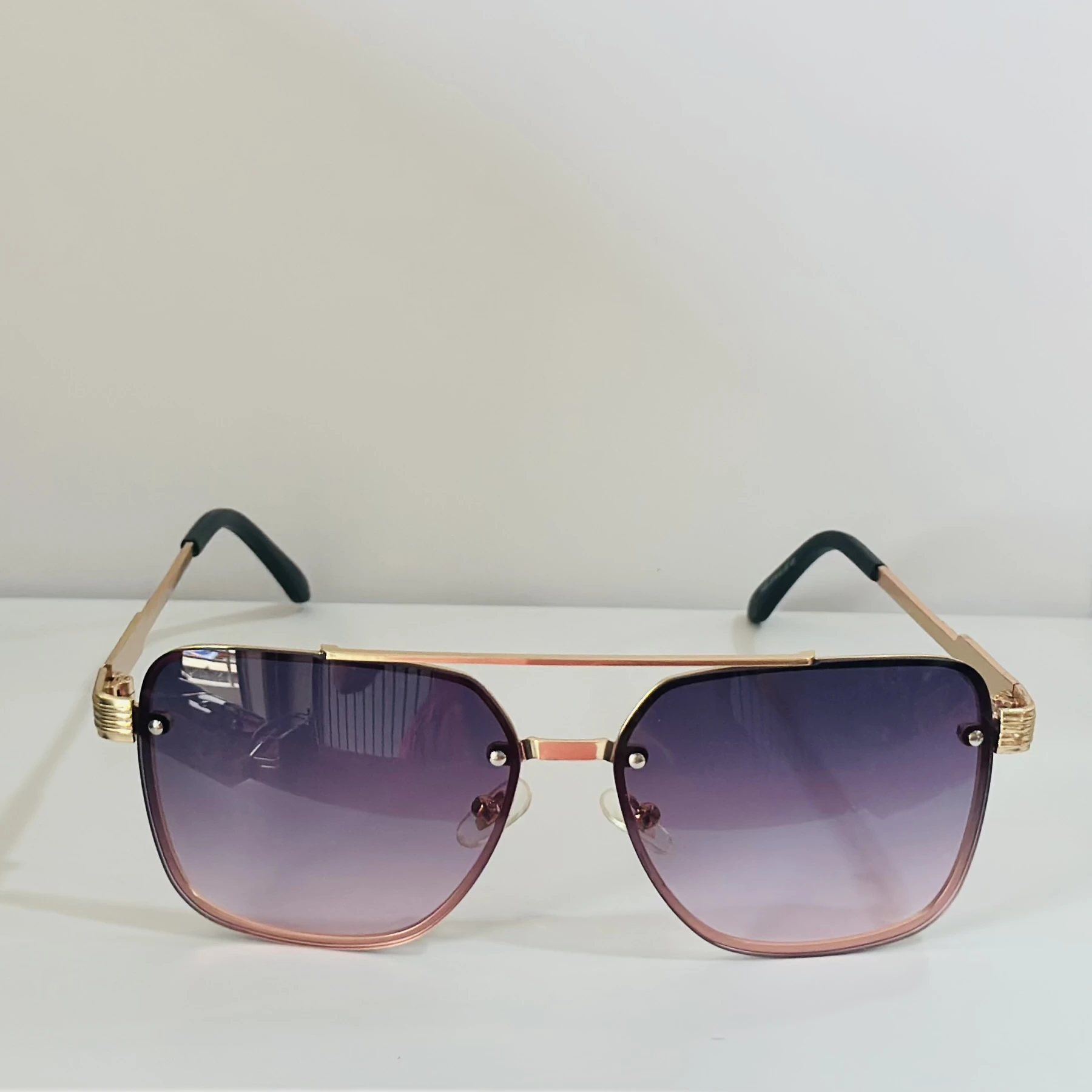 pair of fashionable sunglasses with a gold frame and purple gradient lenses.