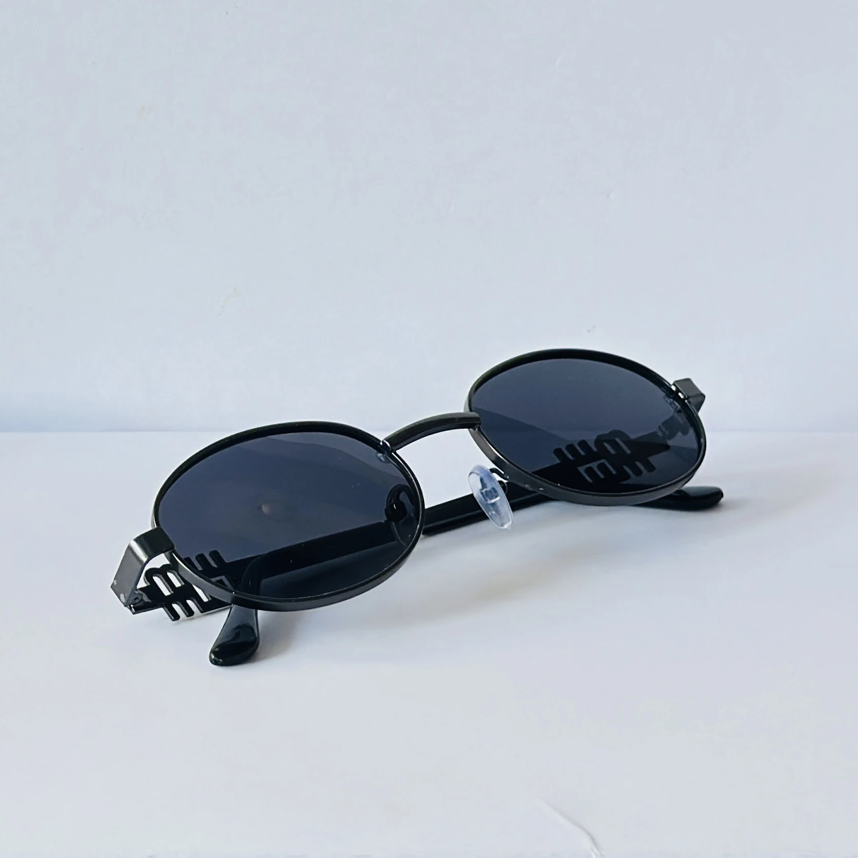 sunglasses featuring a distinct black oval frame and small logo detailing on the lenses
