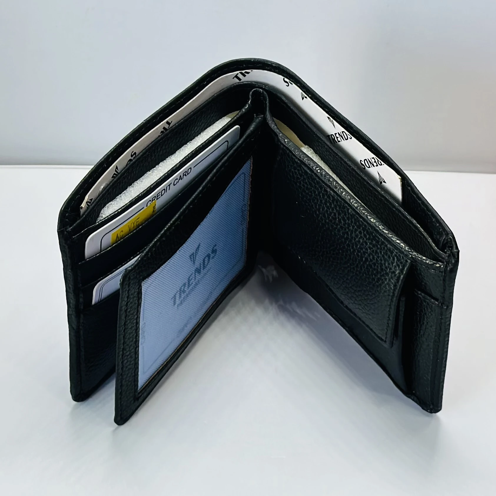 Black leather bifold wallet with a "Trends" logo.