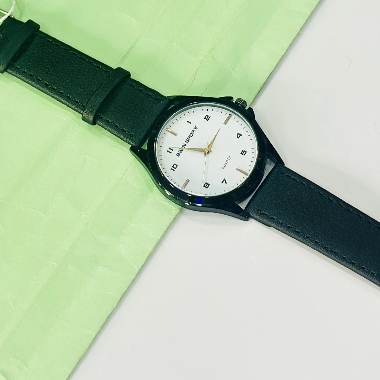 analog watch featuring a white dial, black strap, and quartz movement.