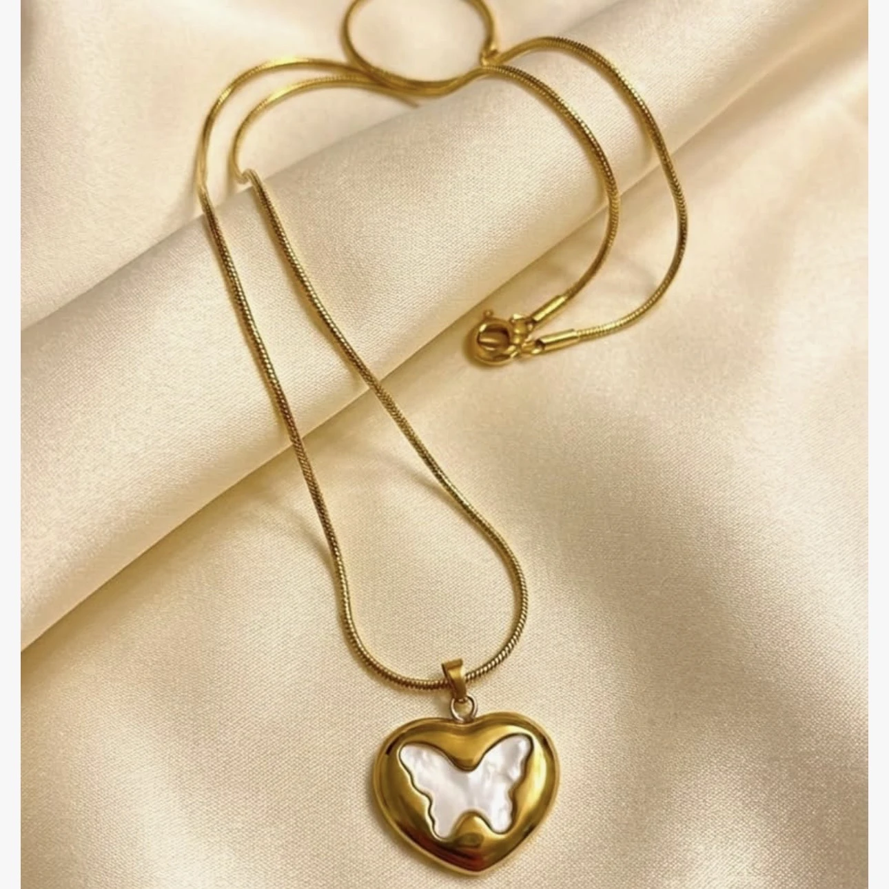 gold-plated necklace features a heart pendant with a white butterfly inlay.
