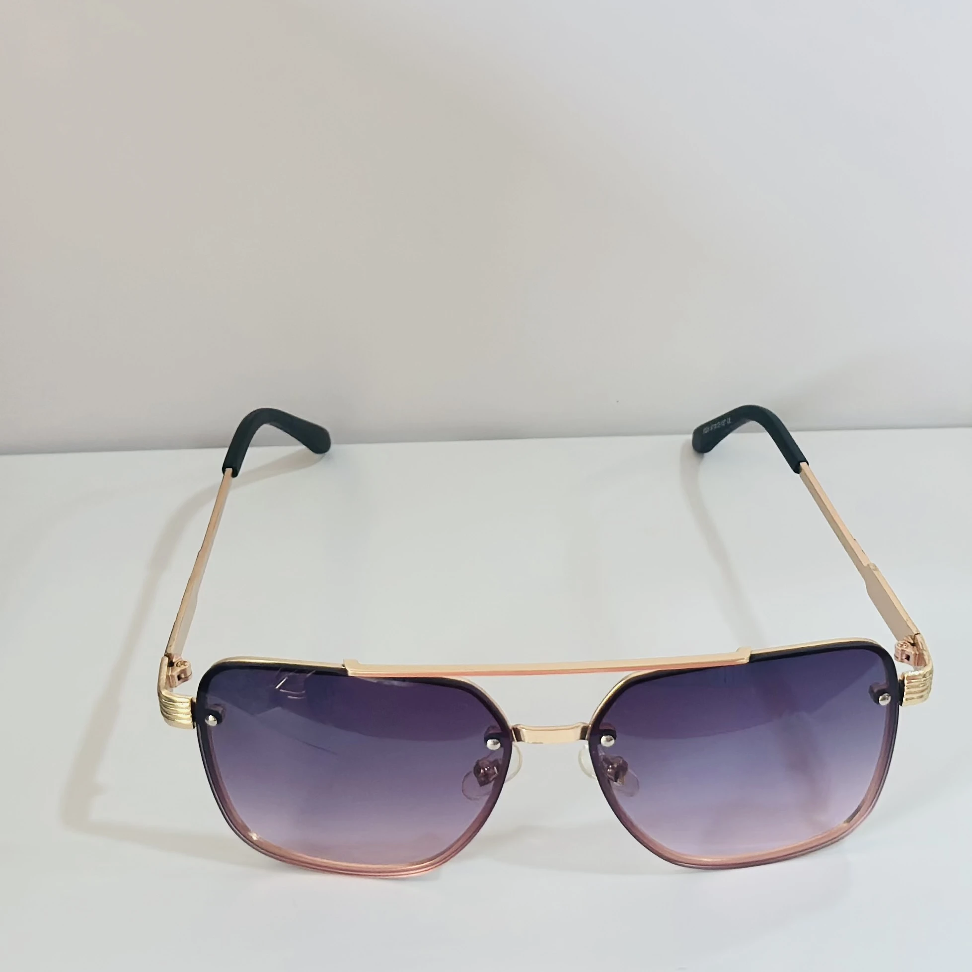 pair of fashionable sunglasses with a gold frame and purple gradient lenses.