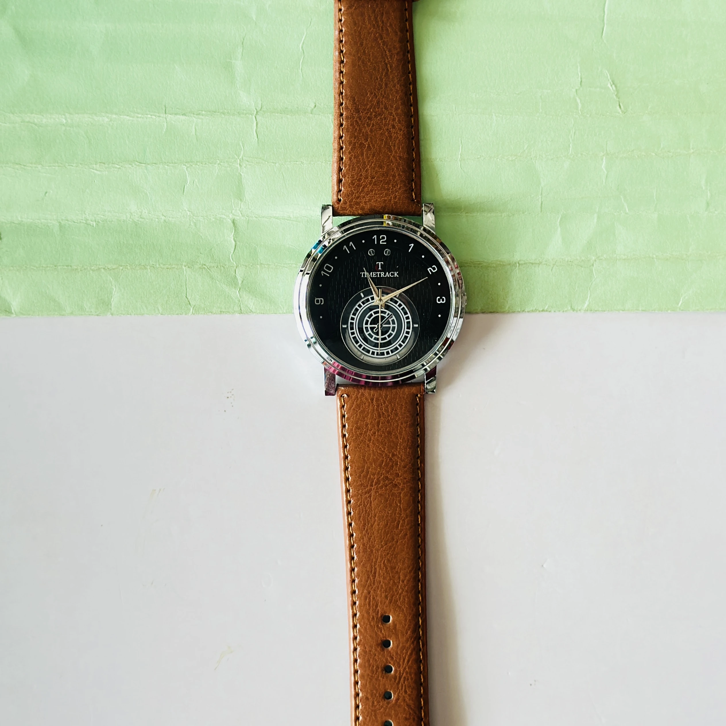 quartz analog watch with a brown leather strap and a black dial
